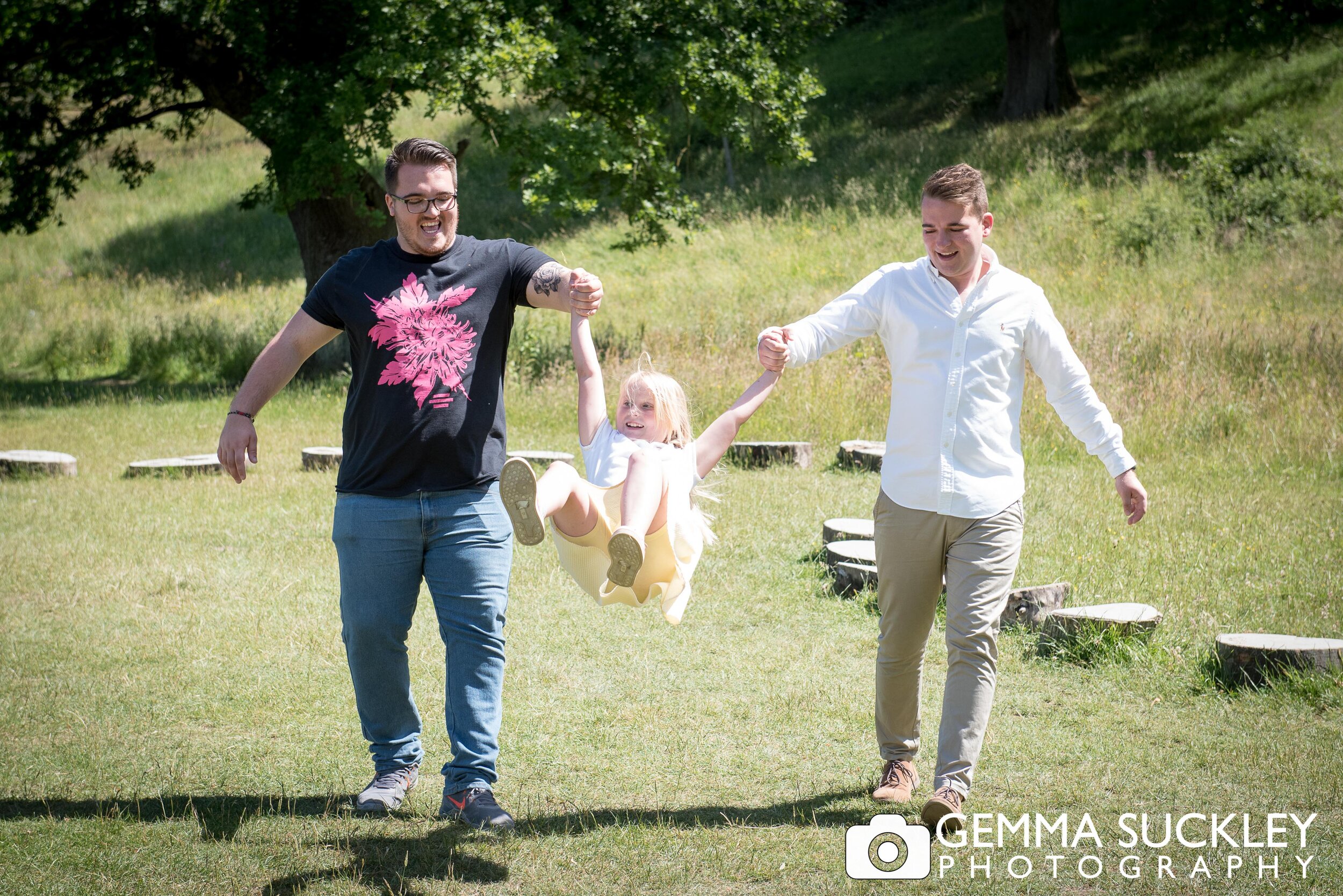 two brothers swinging their sister during a family photo shoot