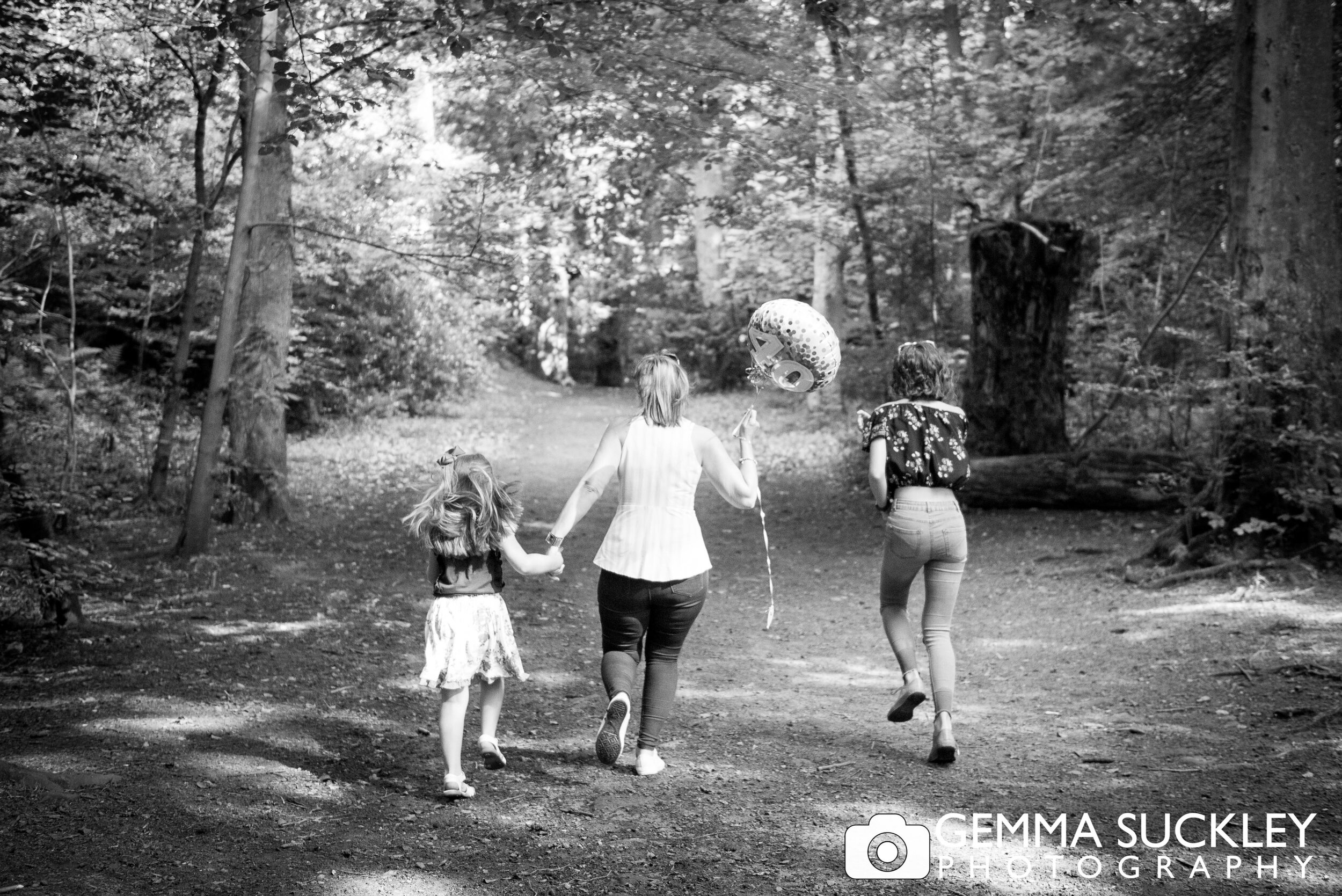 a mother with her two daughters running through the woods