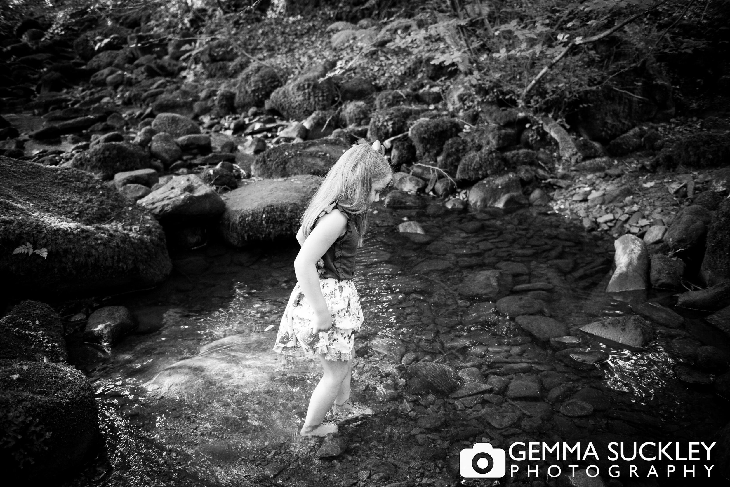 natural family photo of a little girl walking through in a stream