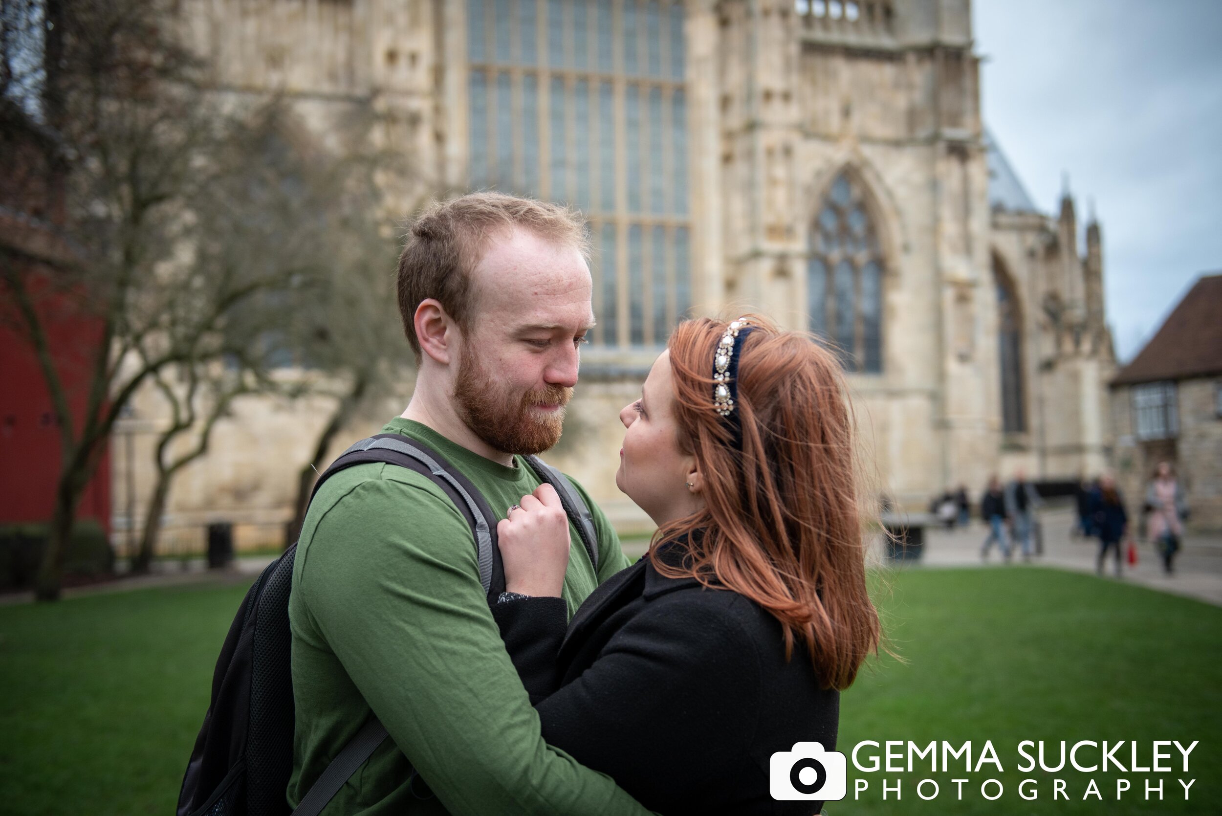natural engagement photo of a couple hugging outside york minster