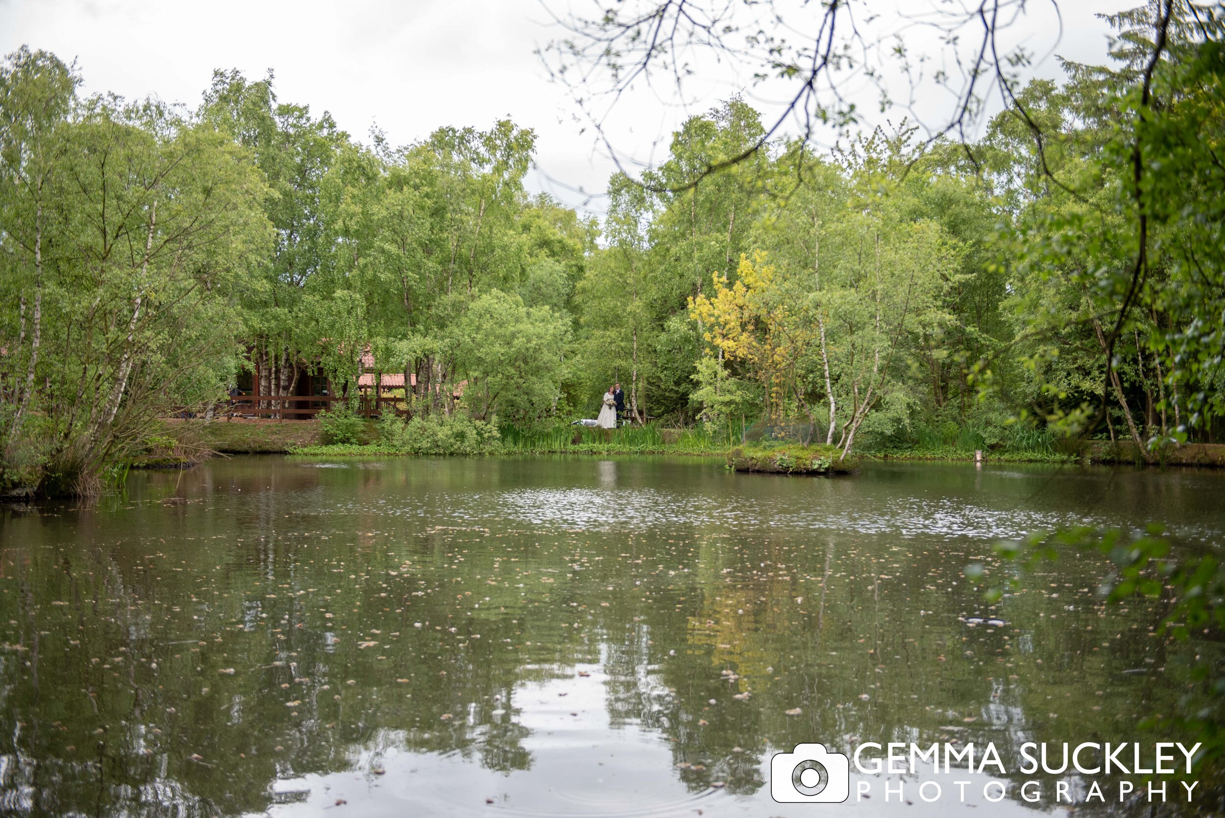 a wedding photo of the bride and groom across the lake at otely chevin country park hotel