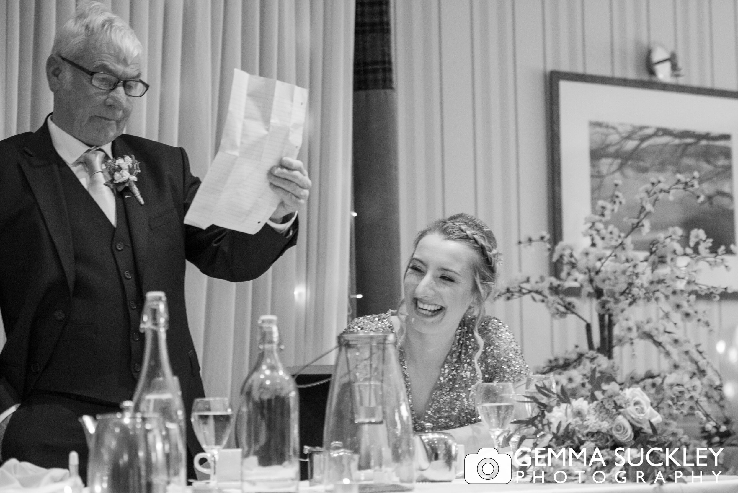 black and white photo of the bridesmaid laughing at father of the brides speech