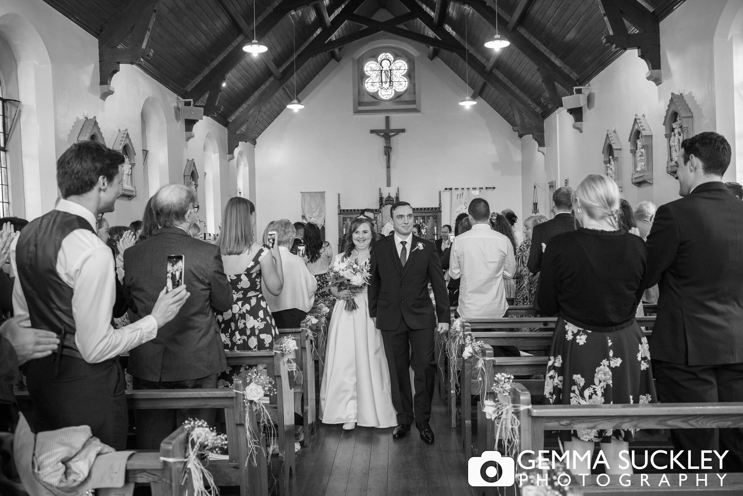 black and white photography of bride walking down the church aisle  