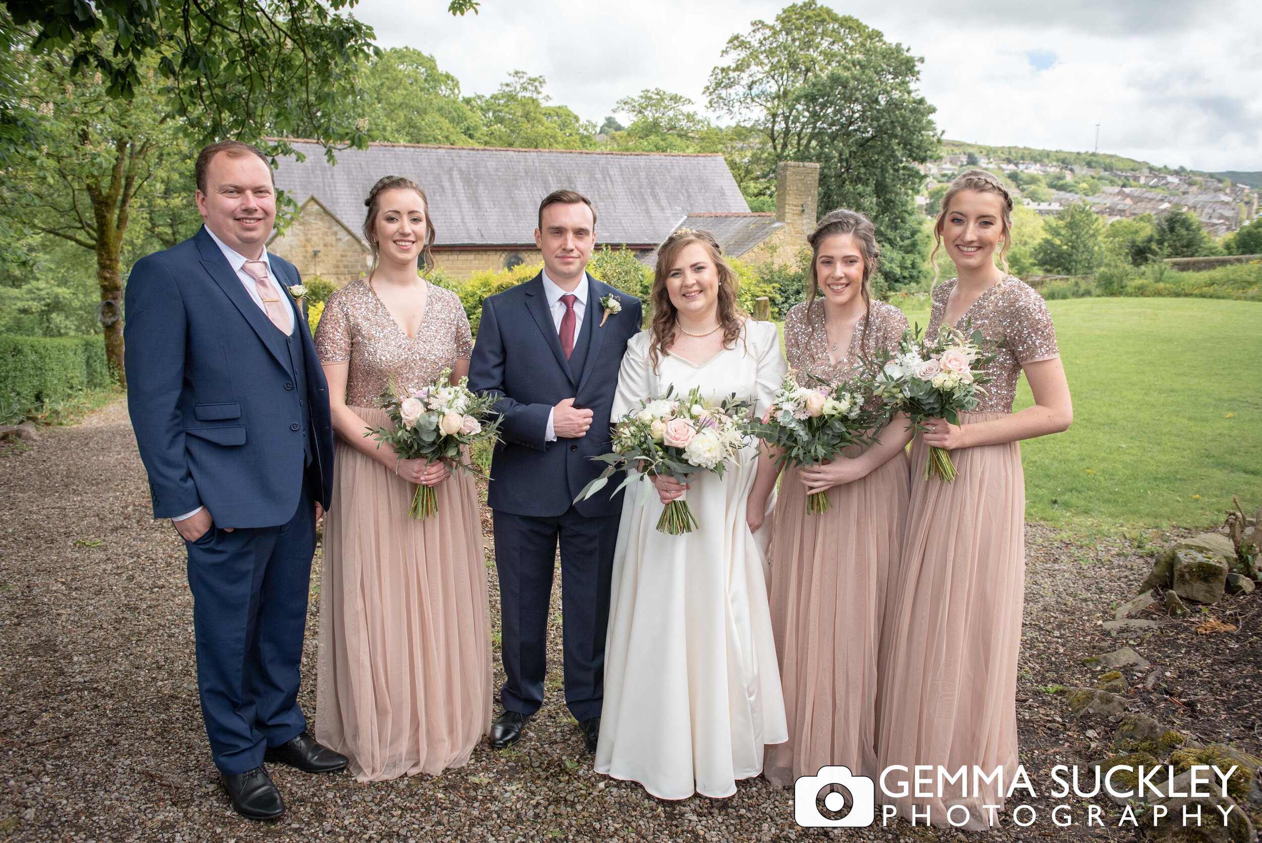 fromal wedding photo of the bridal party outside haworth church