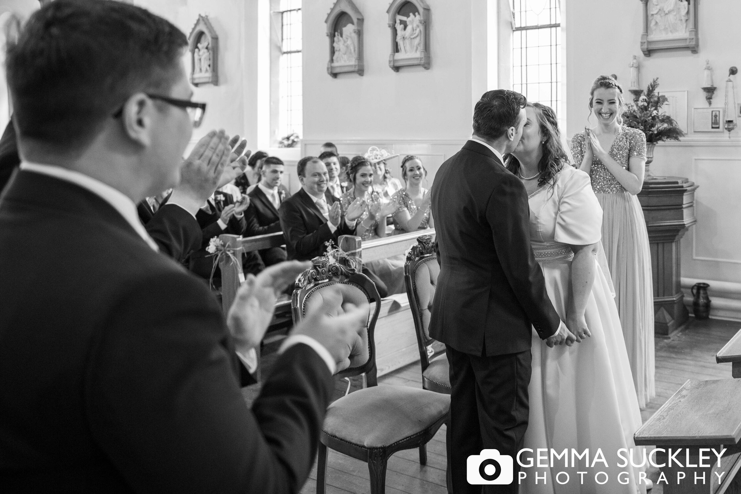 black and white wedding photo of the groom kissing his bride in haworth church