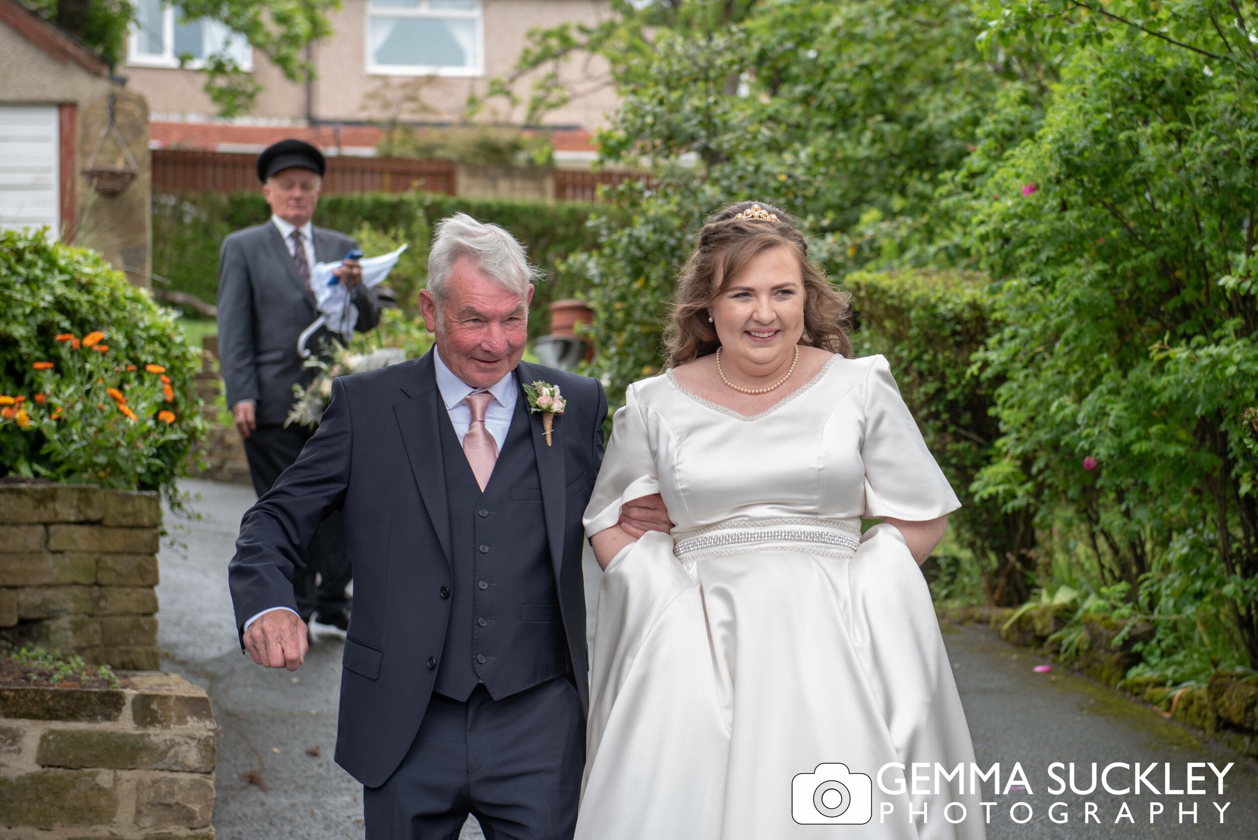 father and bride leaving the house arm in arm