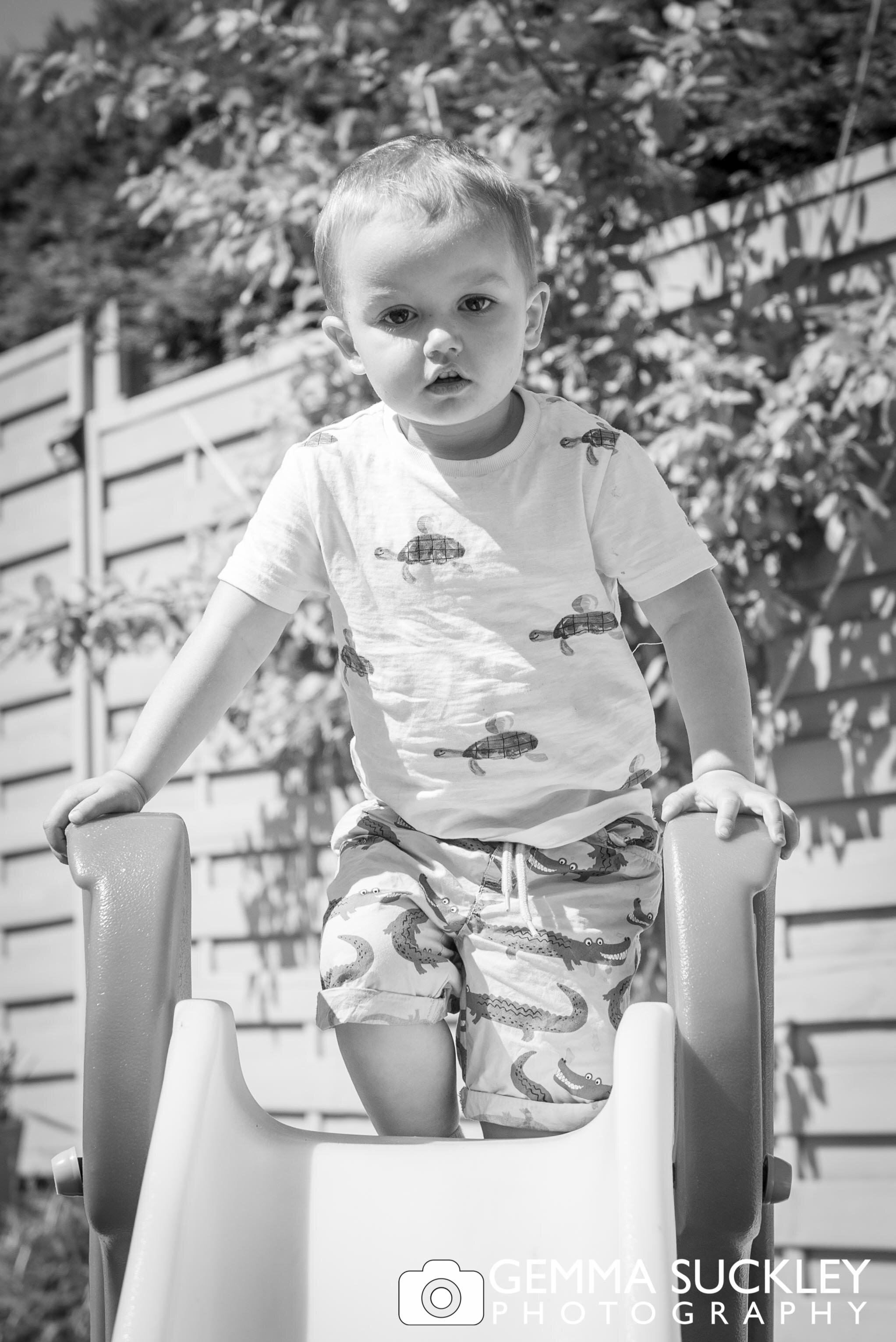 little boy playing on his slide in the garden