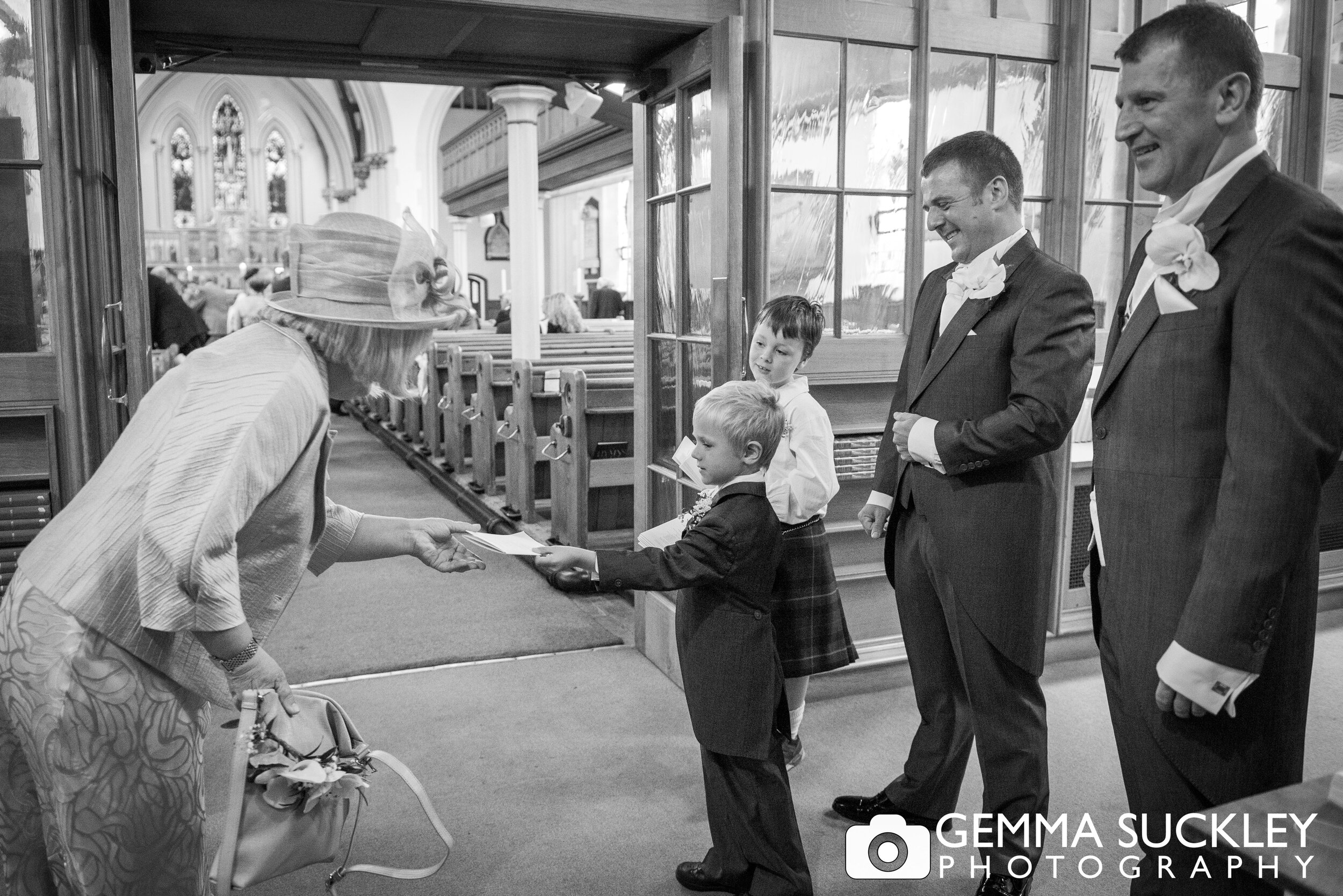 black and white photo of page boys handing out the order of service at harrogate church