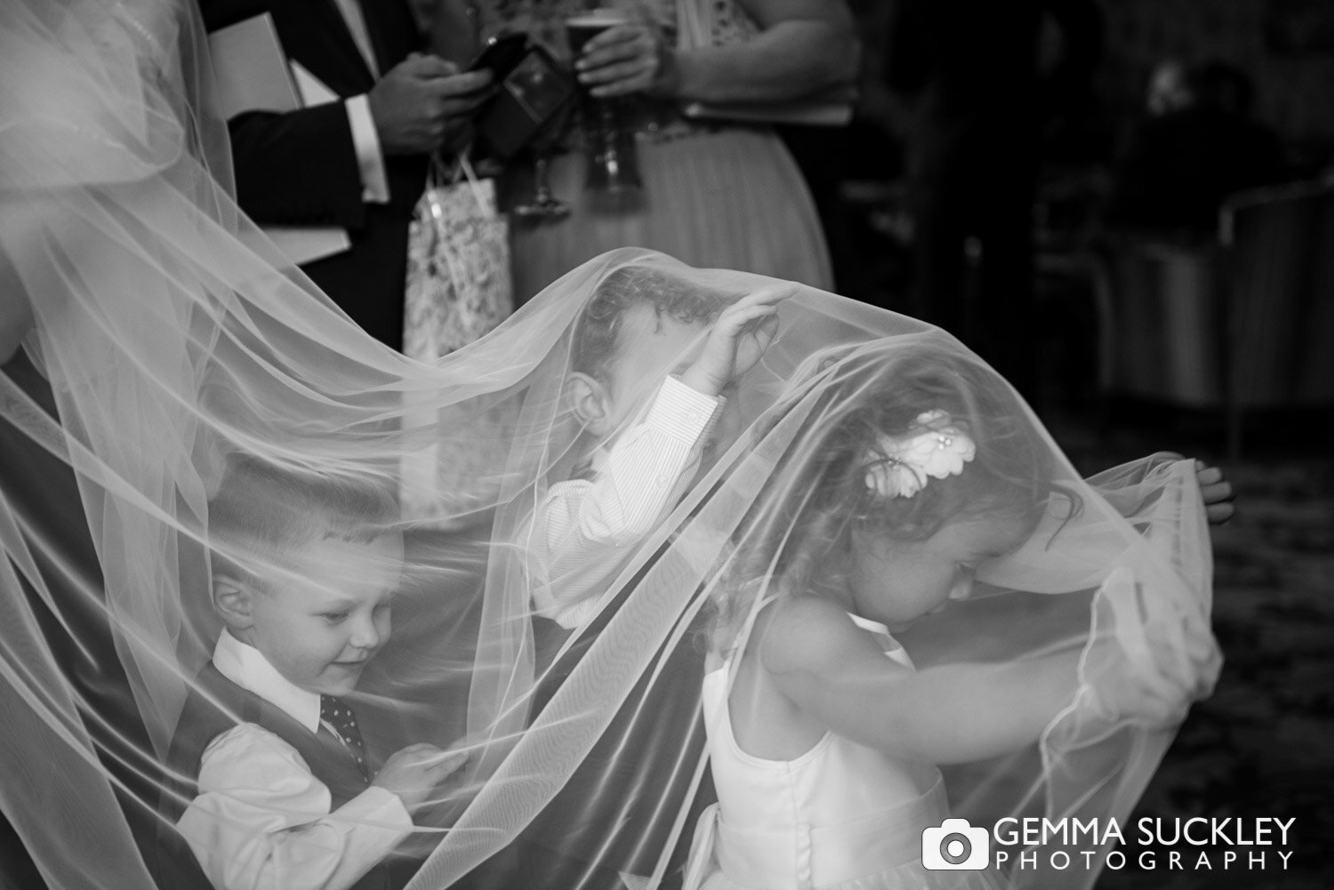 three children playing under the brides veil