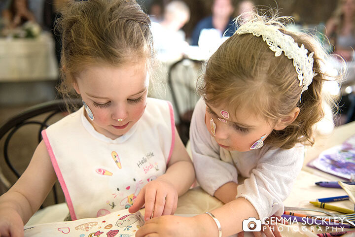 little girls with stickers on their faces seated at an outdoor wedding