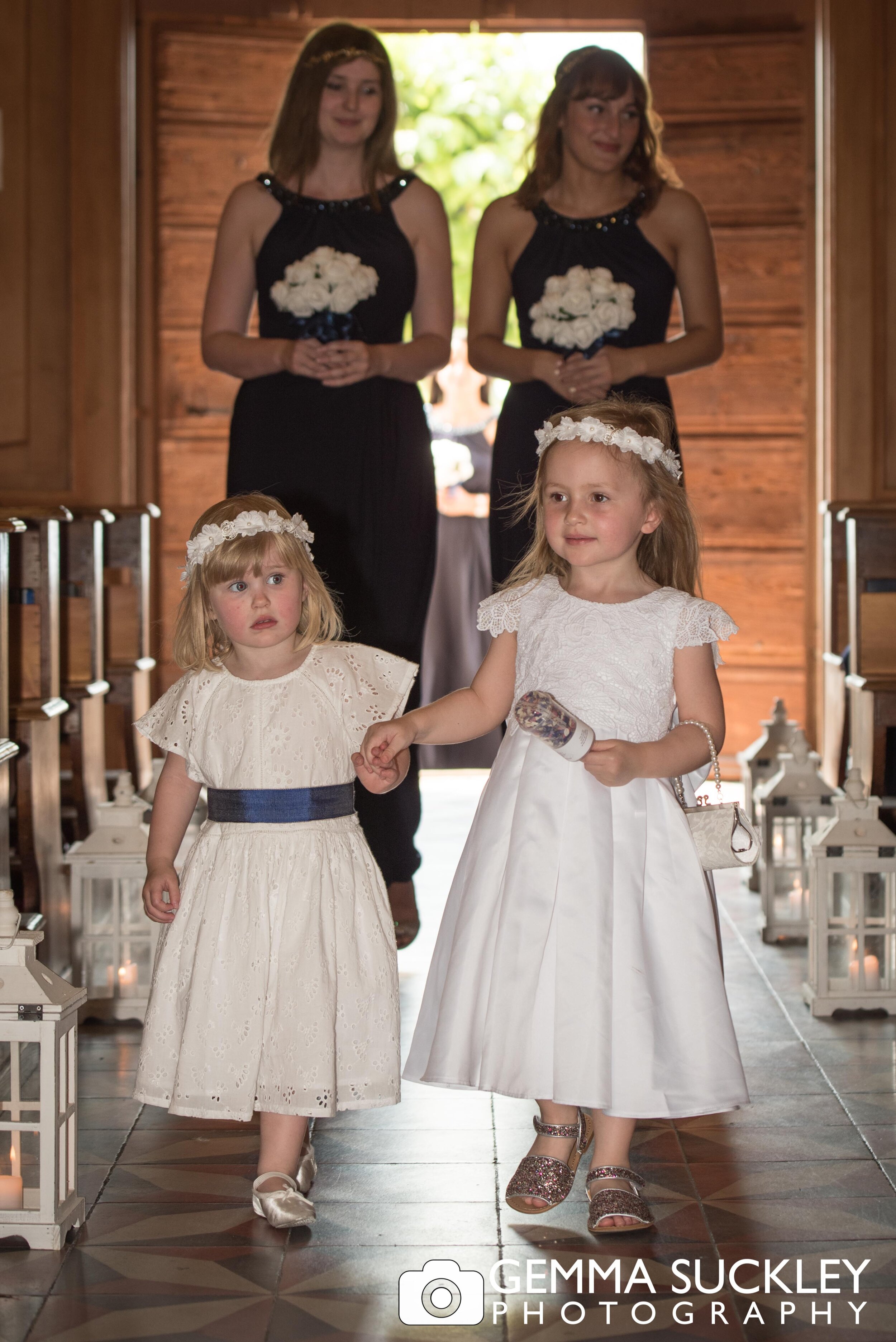 two young flower girls walking down the church aisle