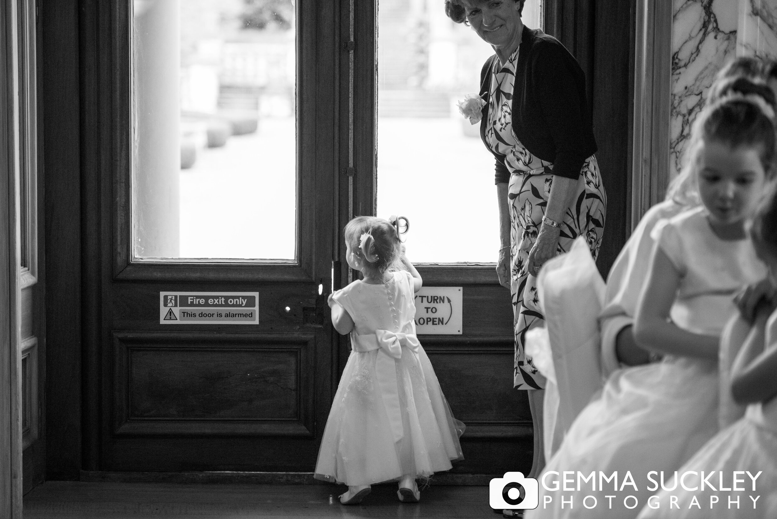 flower girl looking out the exit door on her tip toes