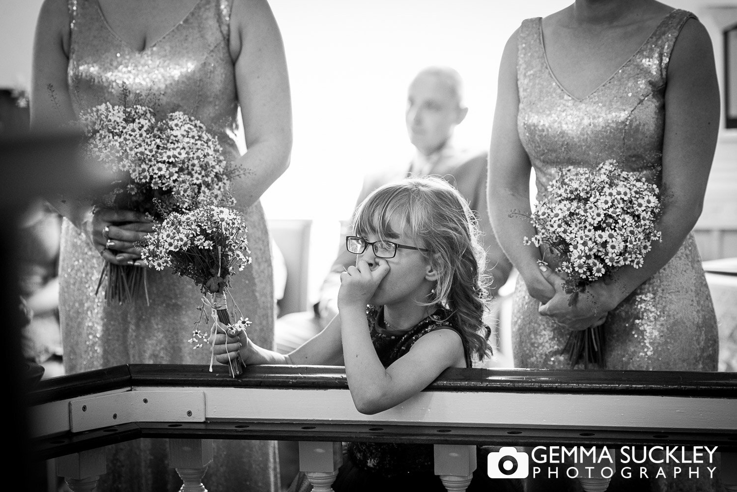 black and white photography of a flower girl sucking her thumb during the wedding ceremony