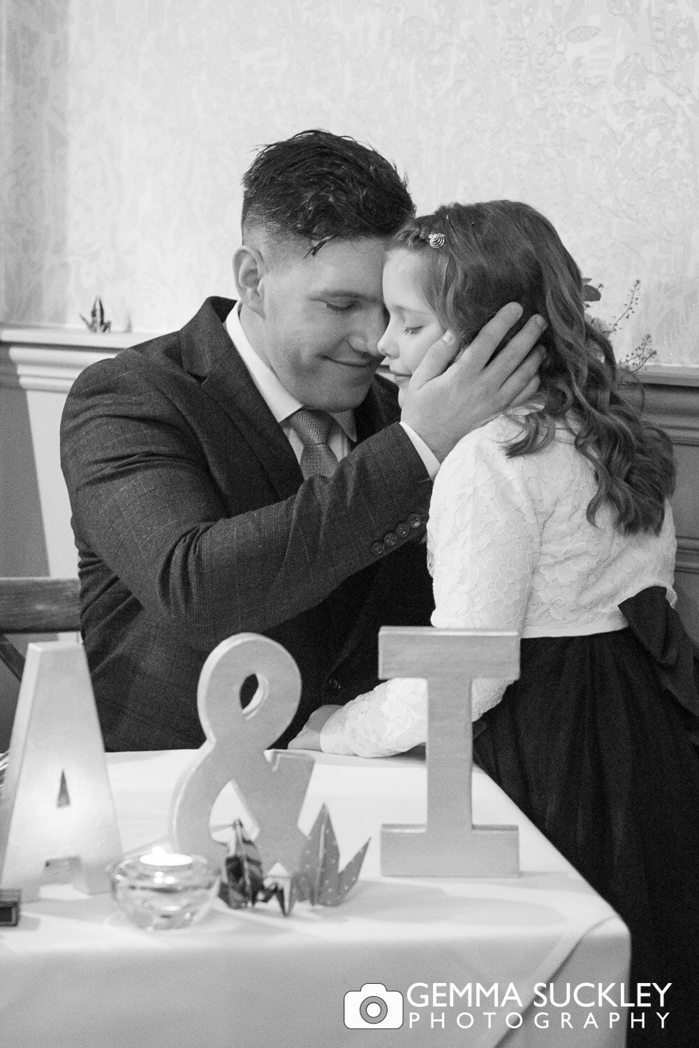 black and white photo of the groom cupping his daughter face in his hands