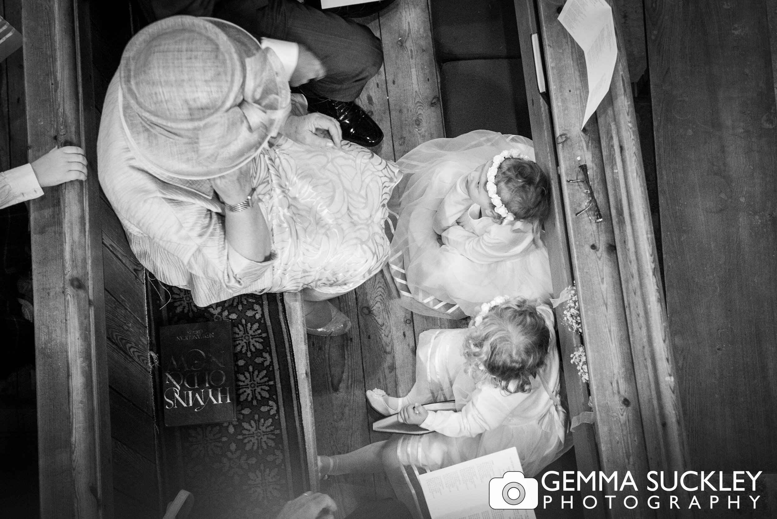 photo from above of two flower girls sitting on the floor between the church pews 