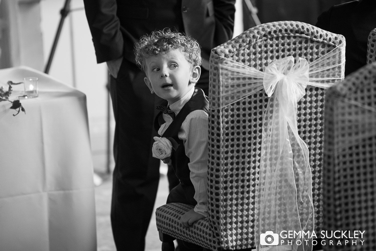 black and white photo of a page boy looking up the aisle for for the bride