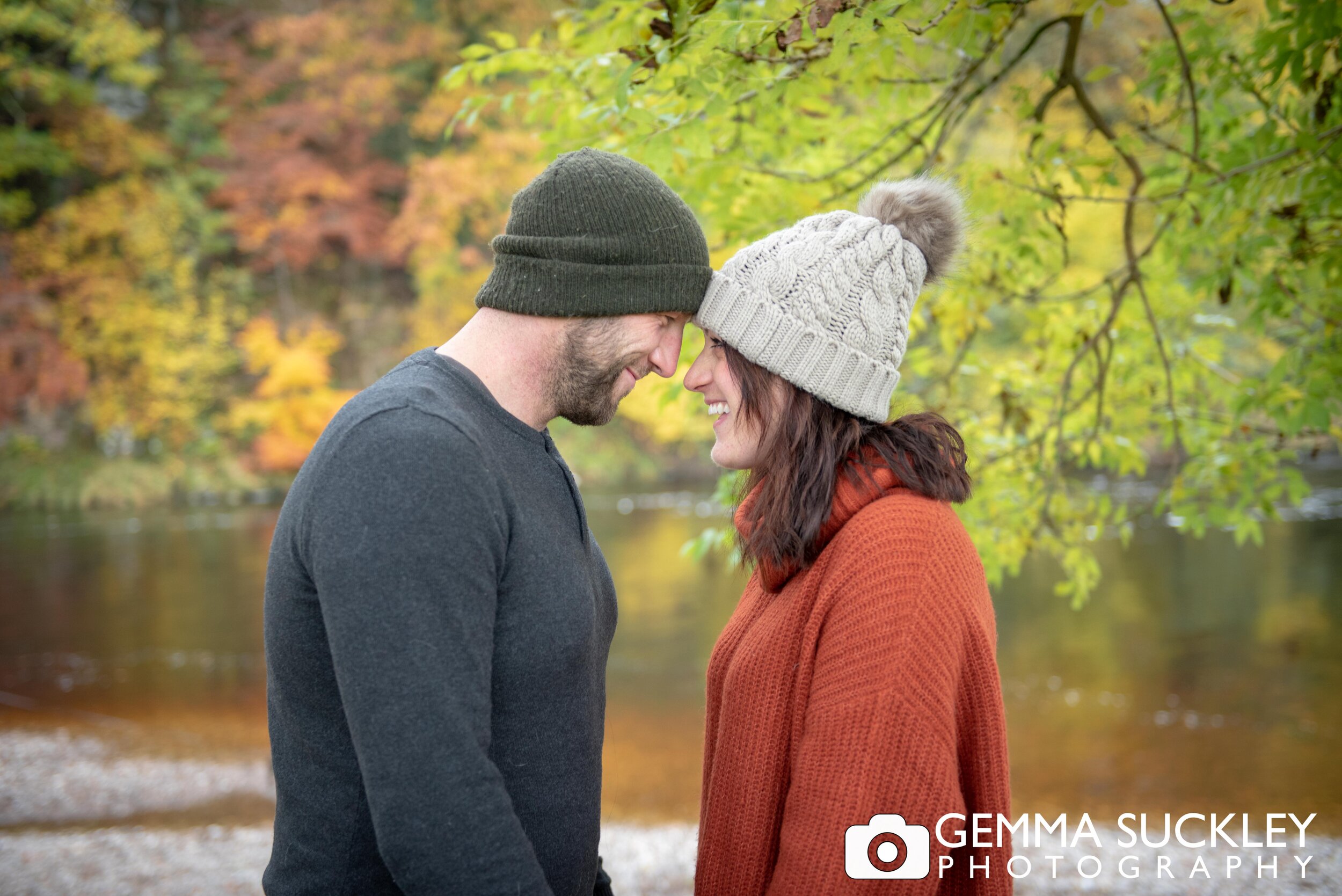 an autumnal photo of a couple wearing wooly hats at bolton abbey 