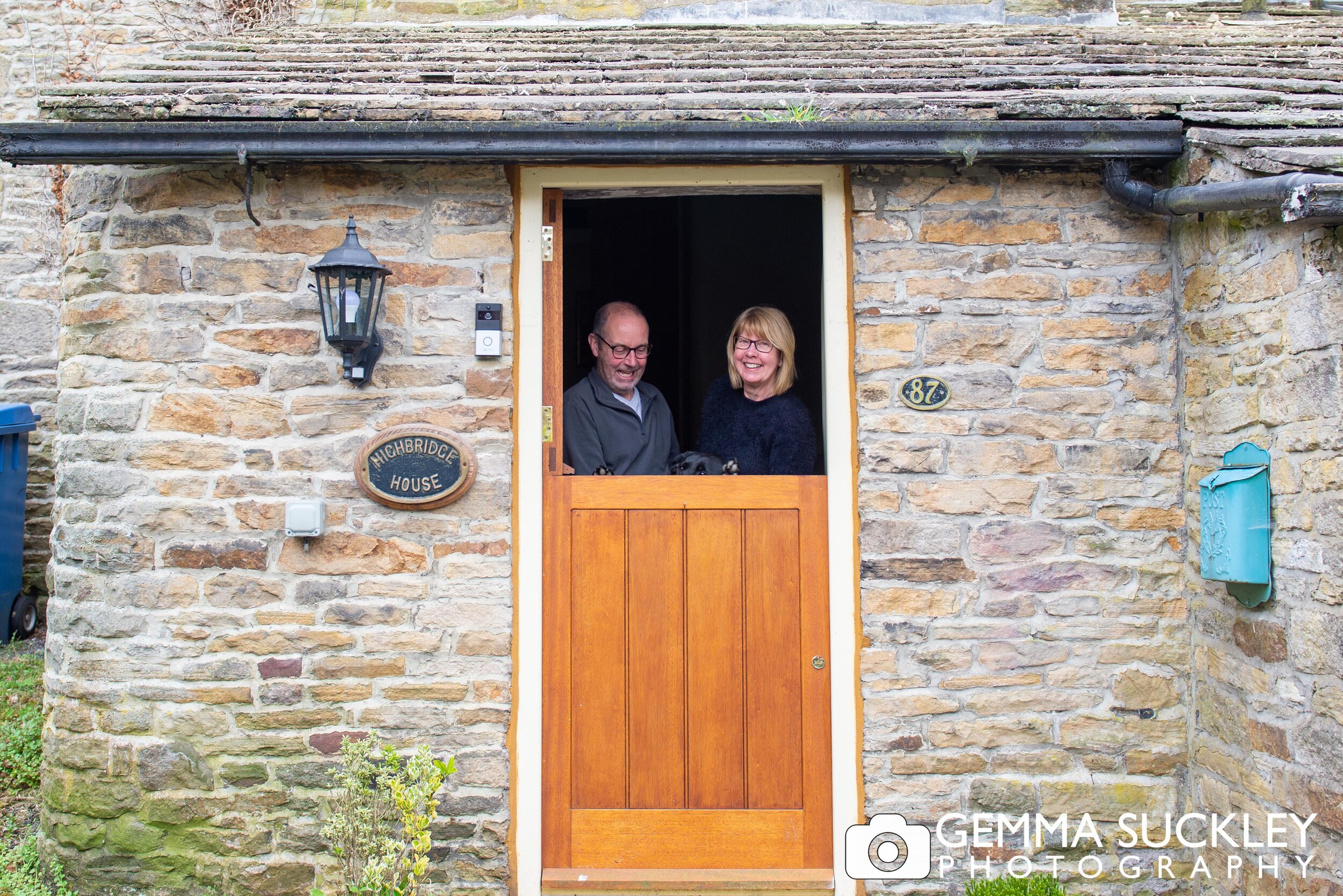 doorstep photo of a couple and their dog trying to see over the stable door