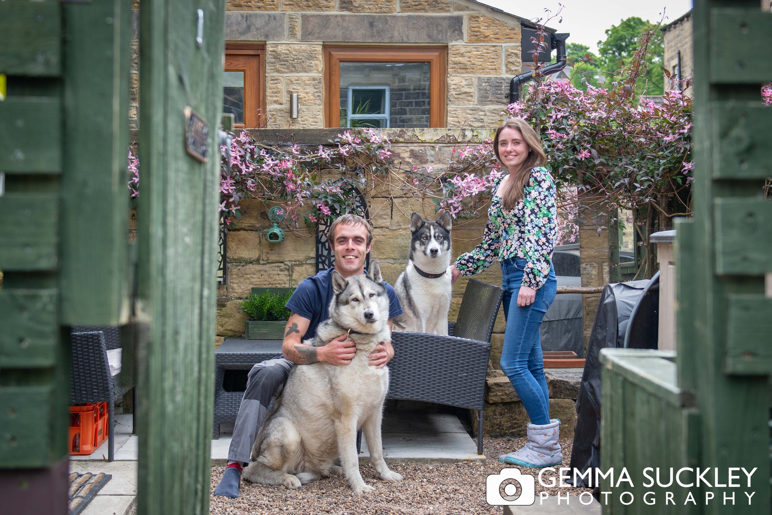 a couple and two huskeys smiling for a doorstep photo in steeton