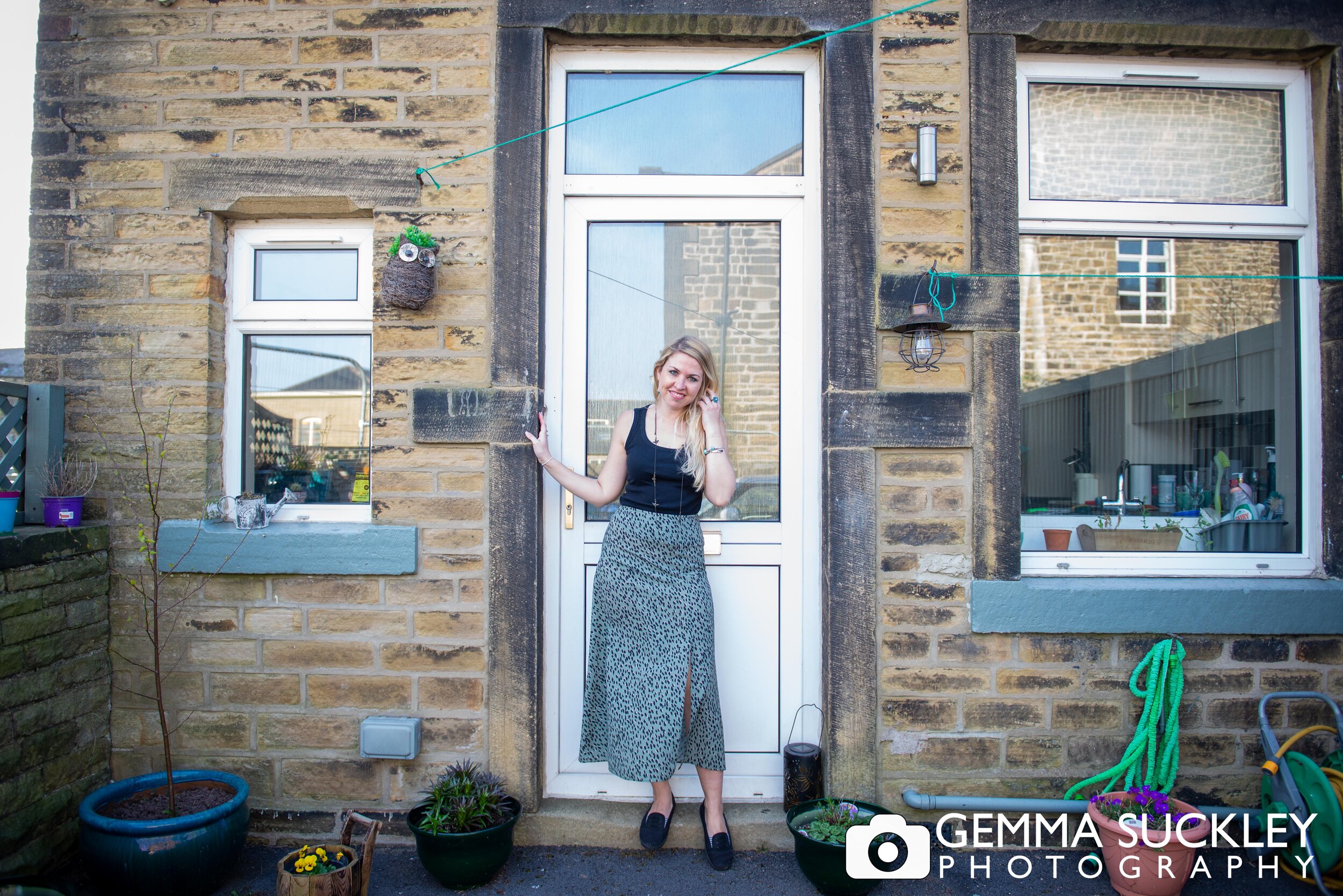 A young woman standing on her doorstep smiling