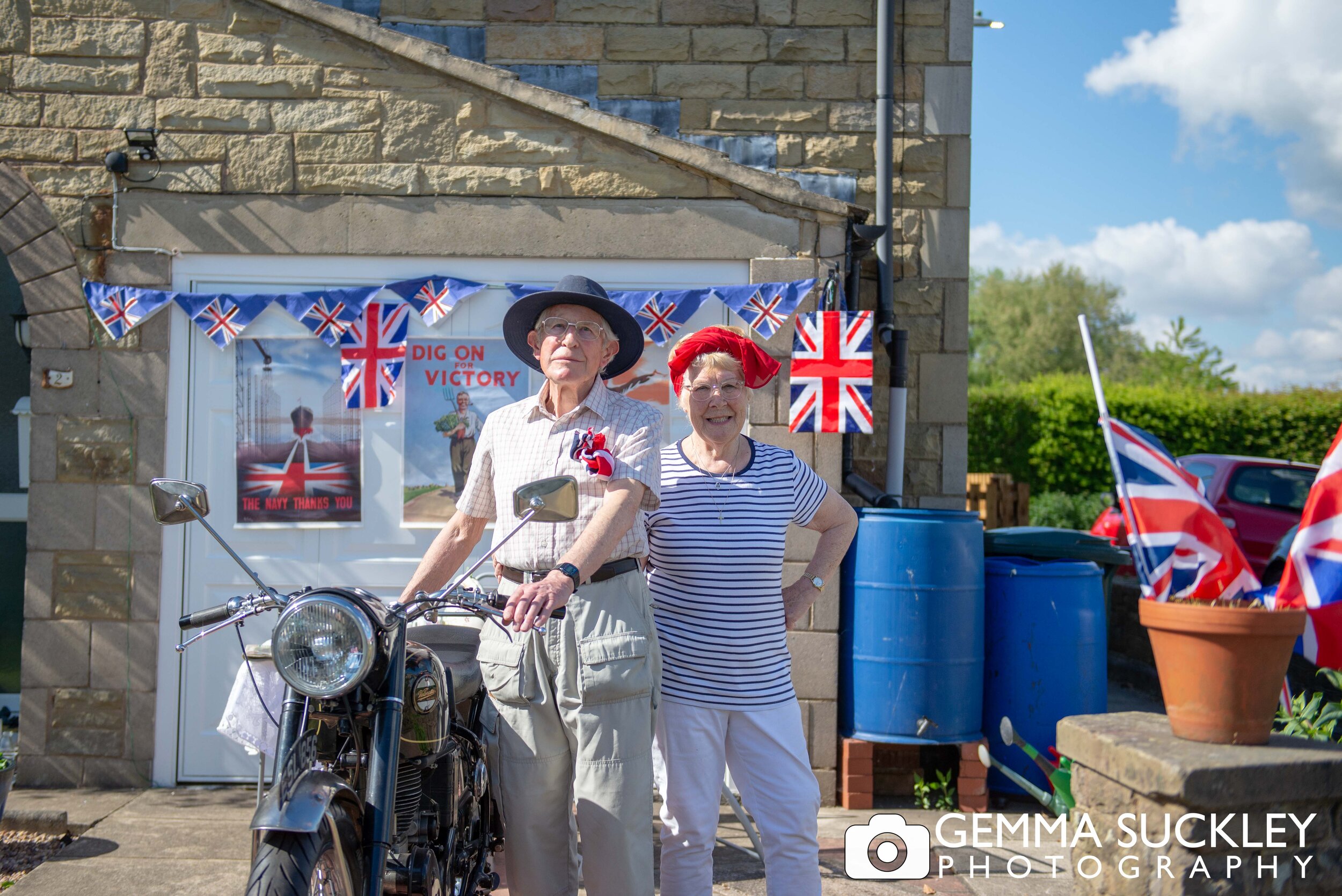 an elderly couple in fancy dress with an old mototcyle on ve day 