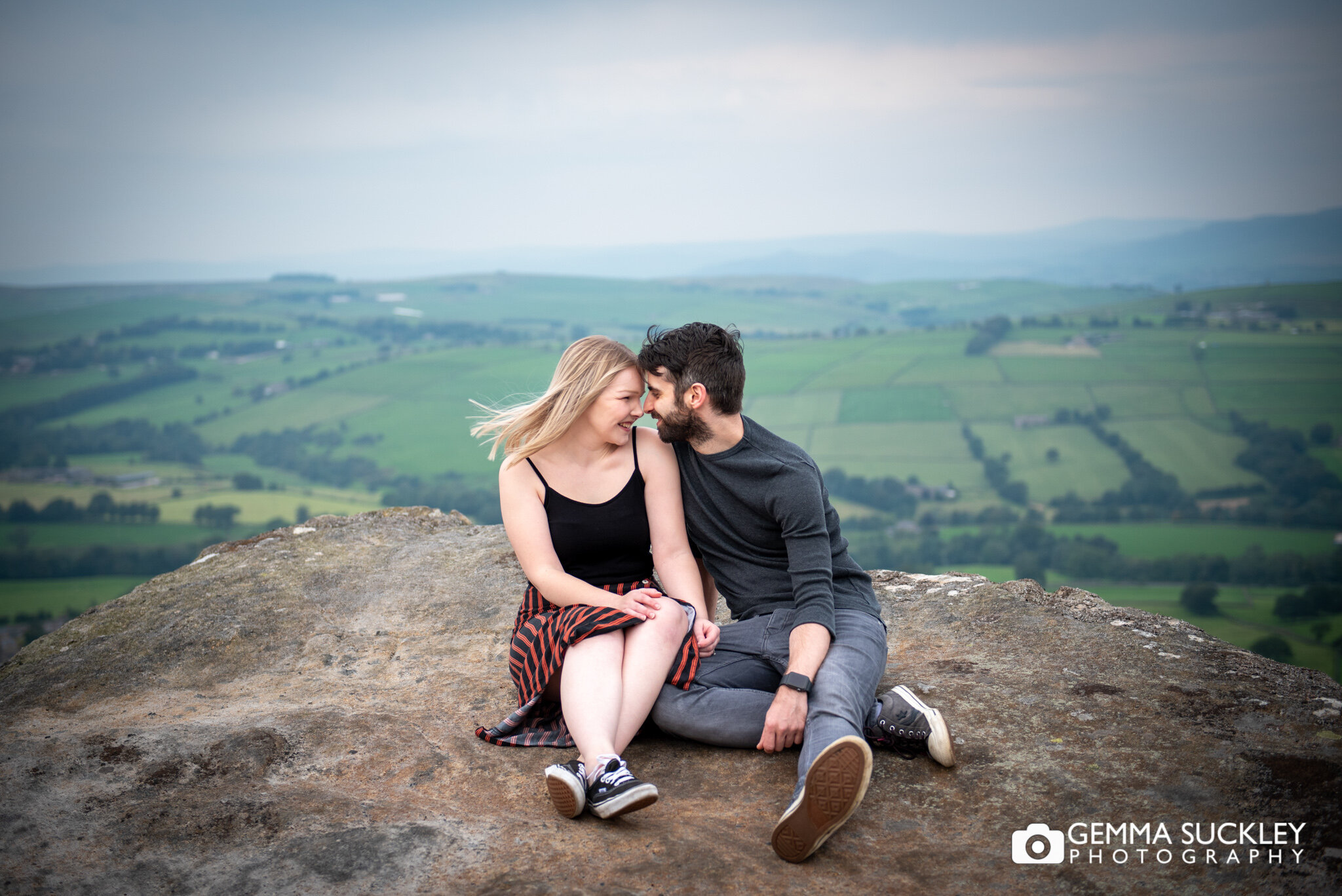an engaged couple sitting on the rock face on cowling moor