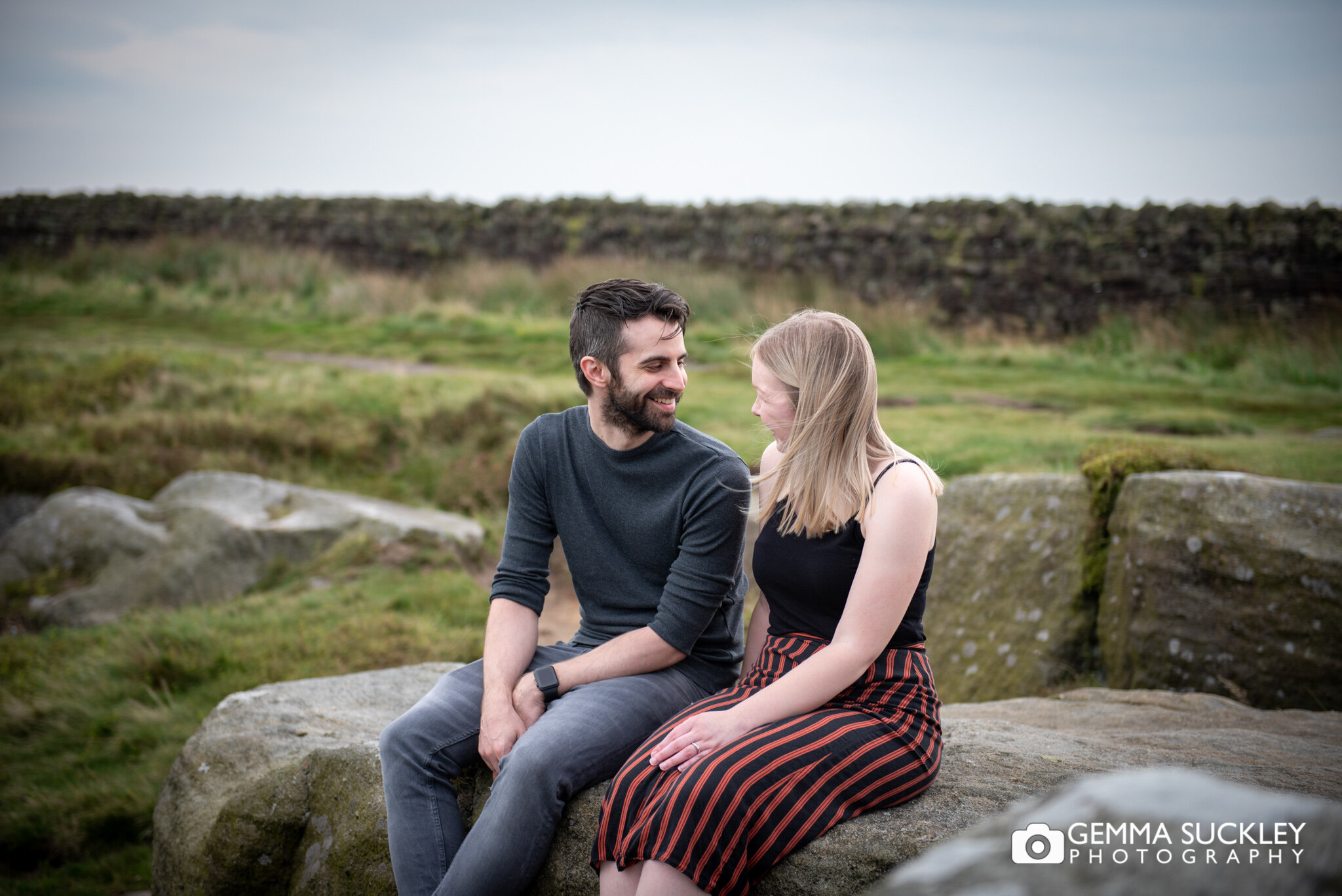 an engaged couple sat side by side on cowling moor