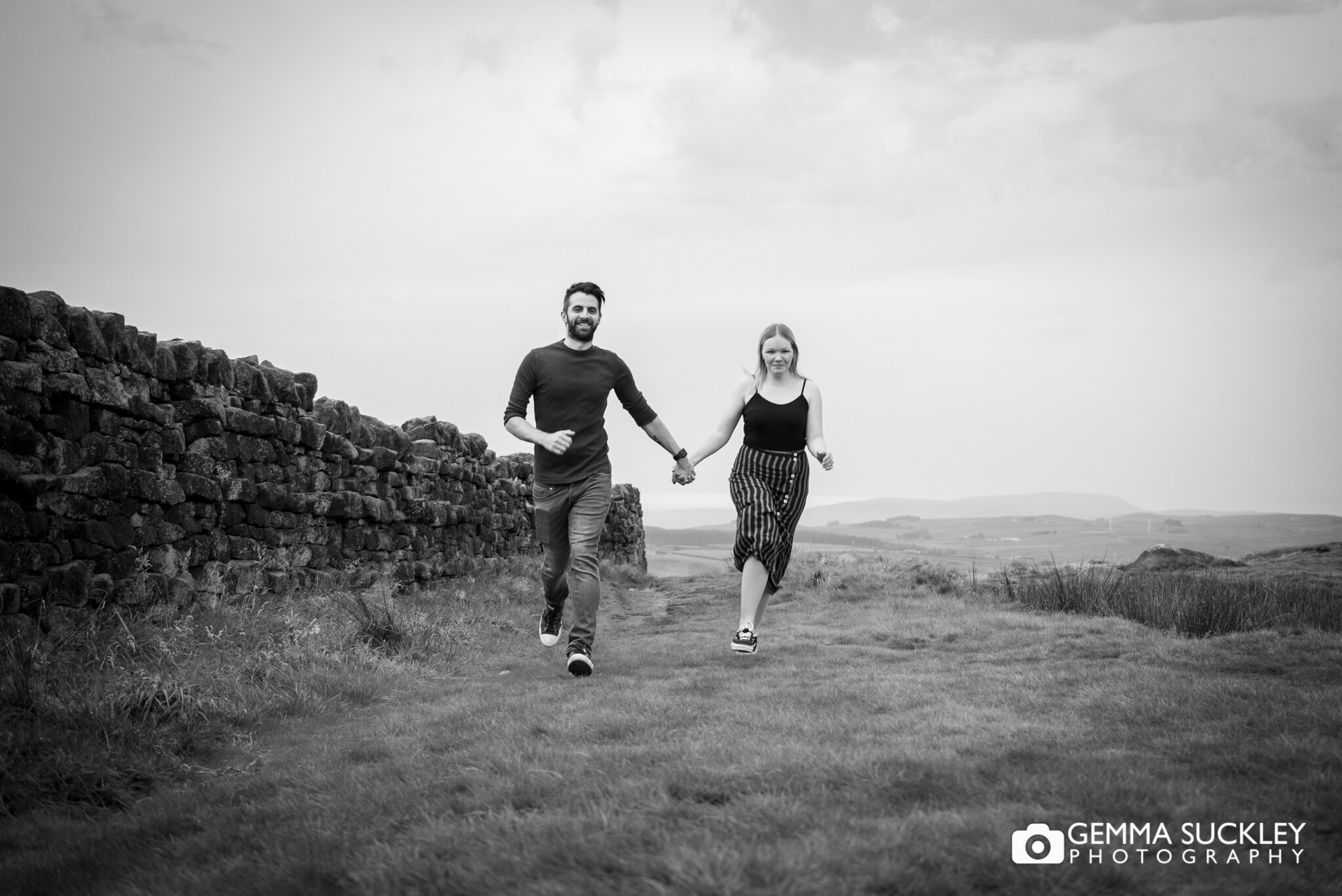 black and white photo of a couple laughing and running on cowling moor