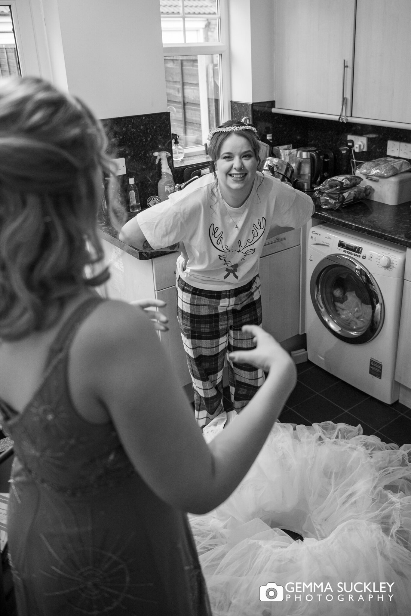 a bride laughing as her bride explains how to step into her wedding dress