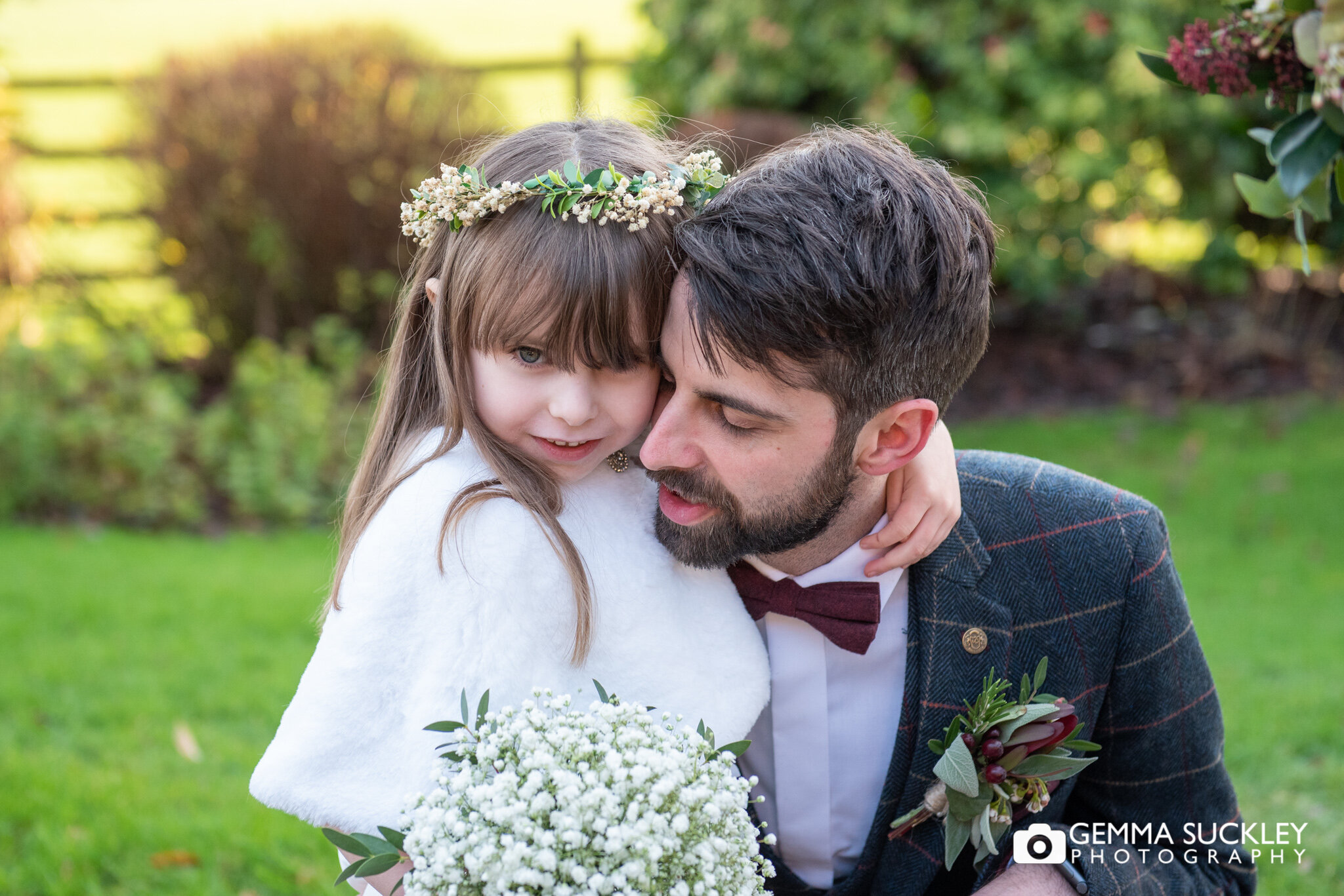 a groom cuddles his daughter, the flower girl