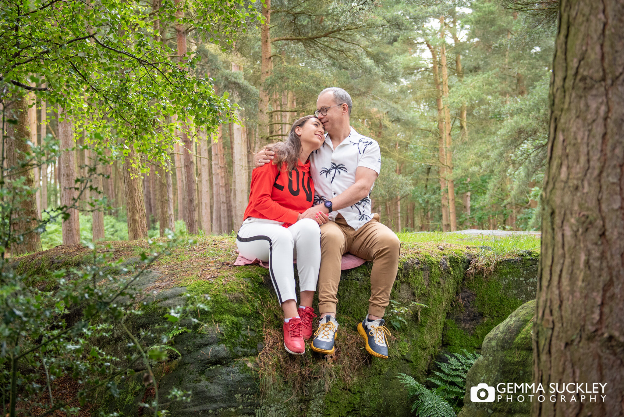 a couple sitting in harden woods during a photoshoot