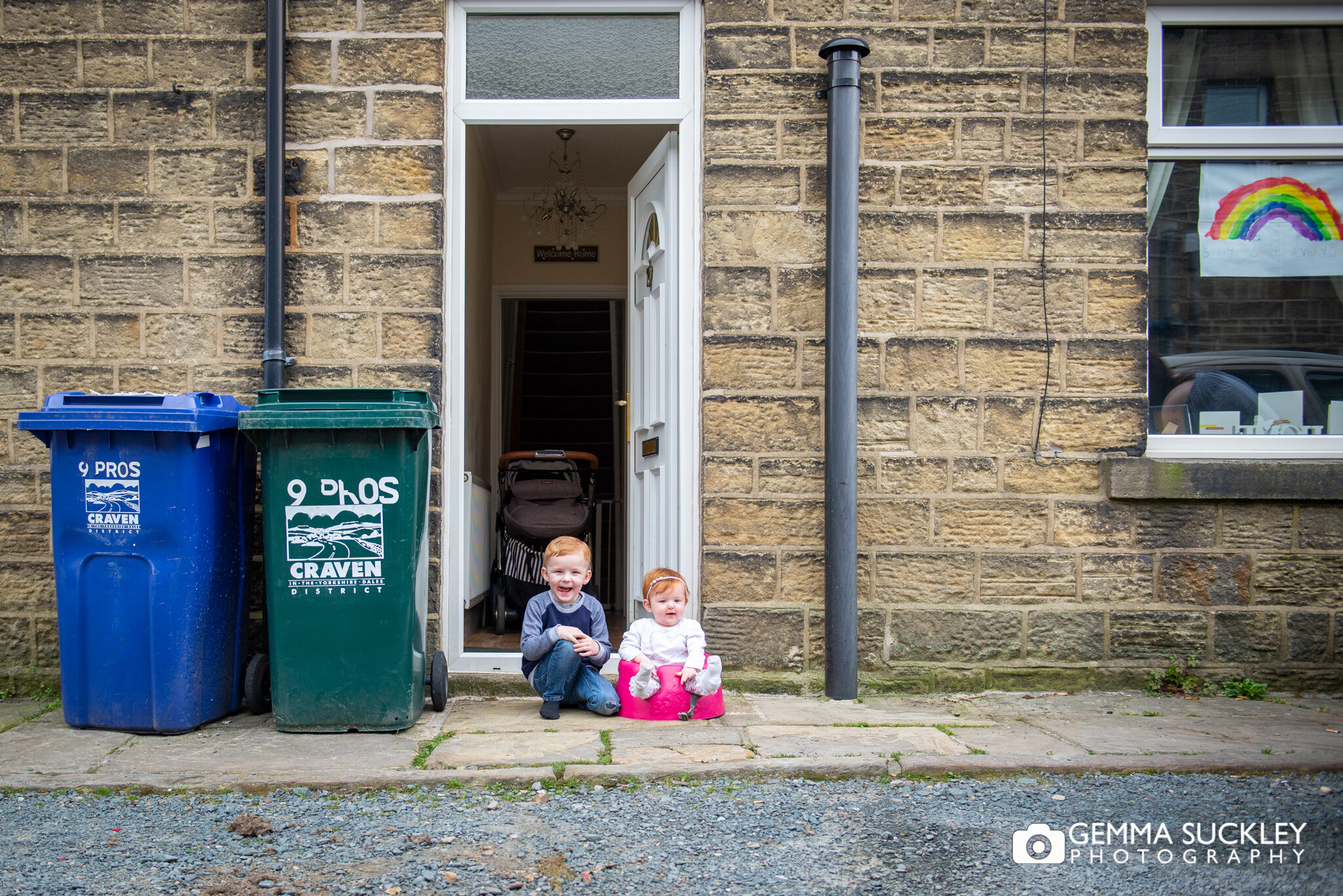 a doorstep portrait of a little boy and his baby sister during lockdown
