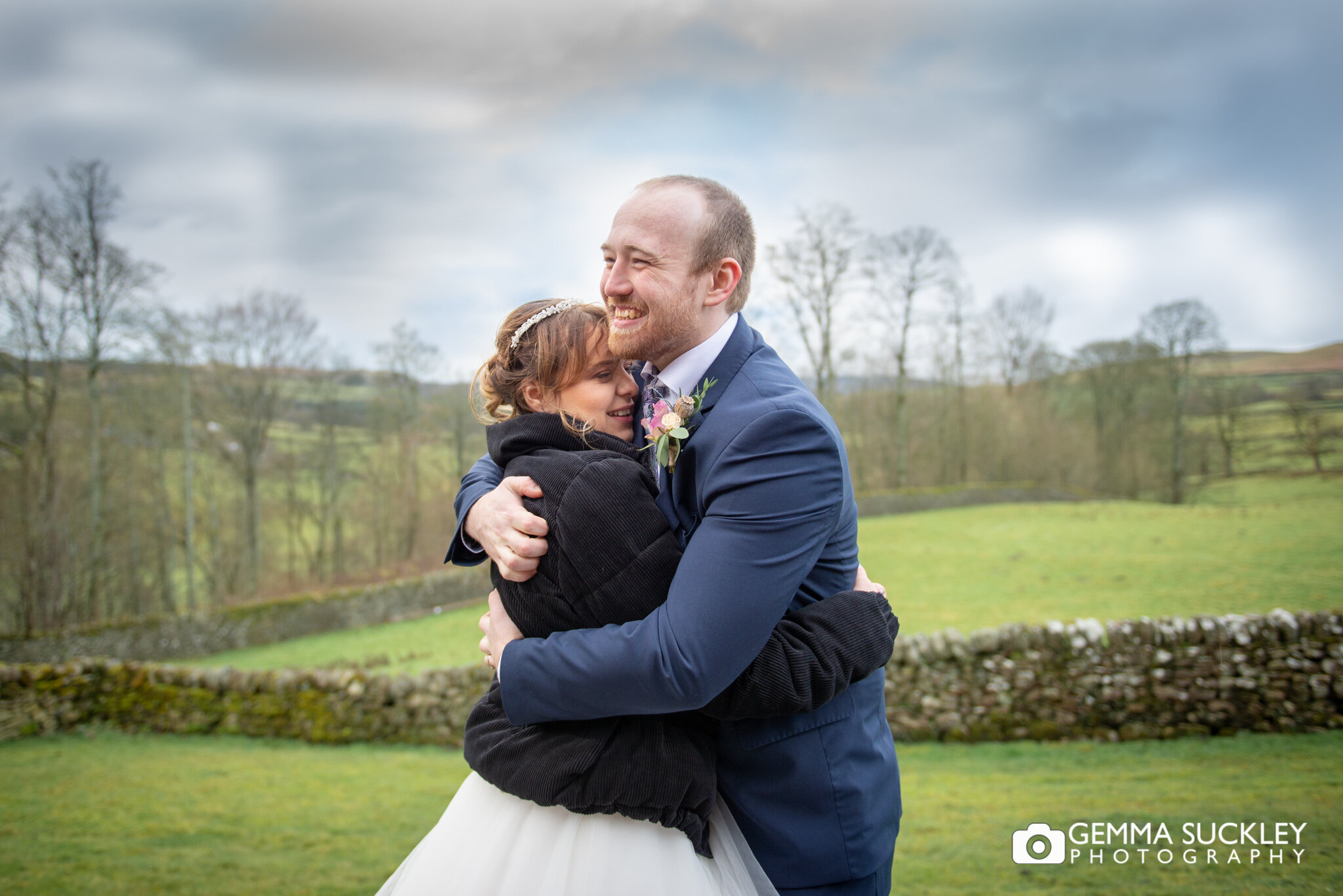 a bride and groom embrace with the yorkshire dales landscape behind