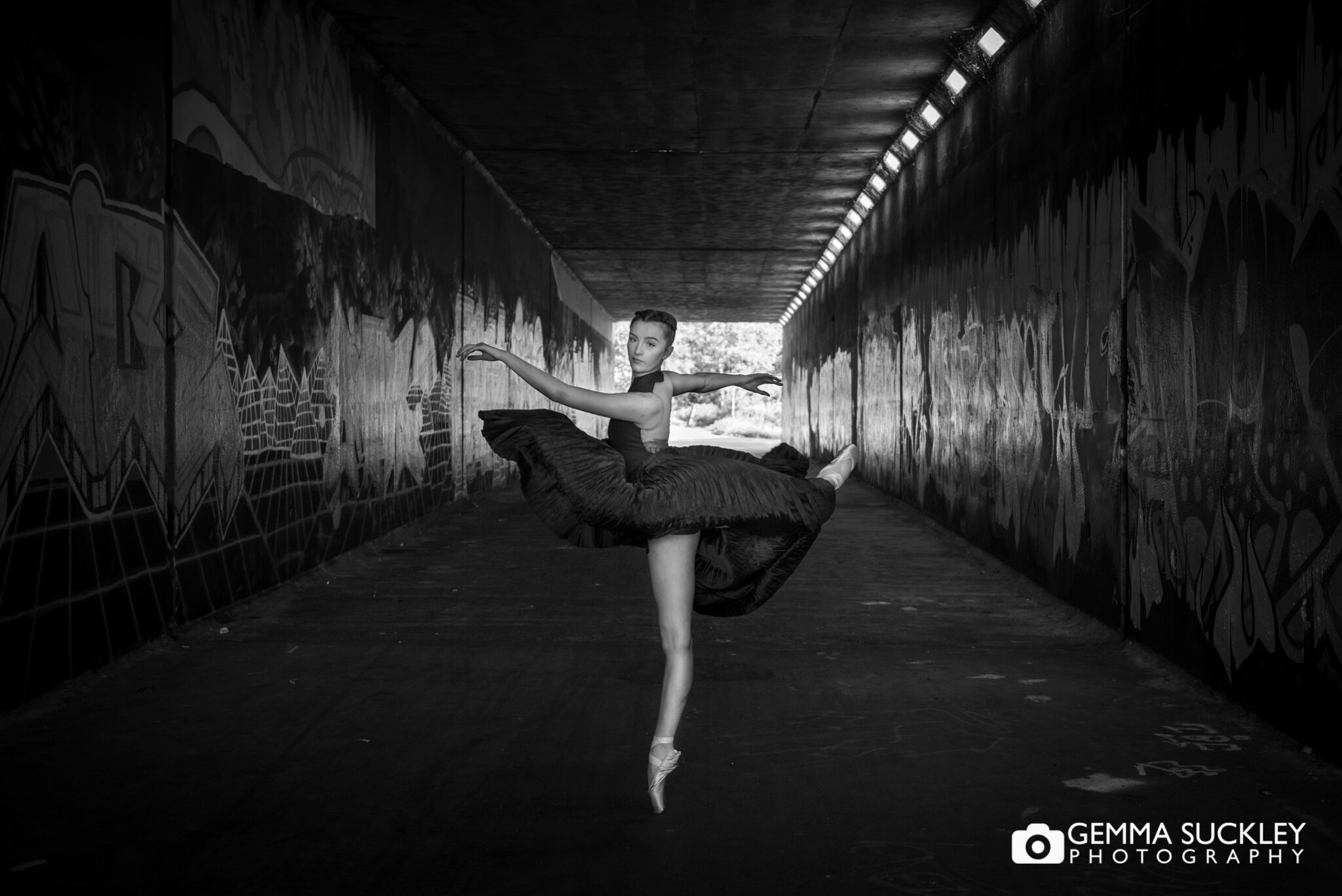 black and white photo of a young ballet dancer in a tunnel dancing