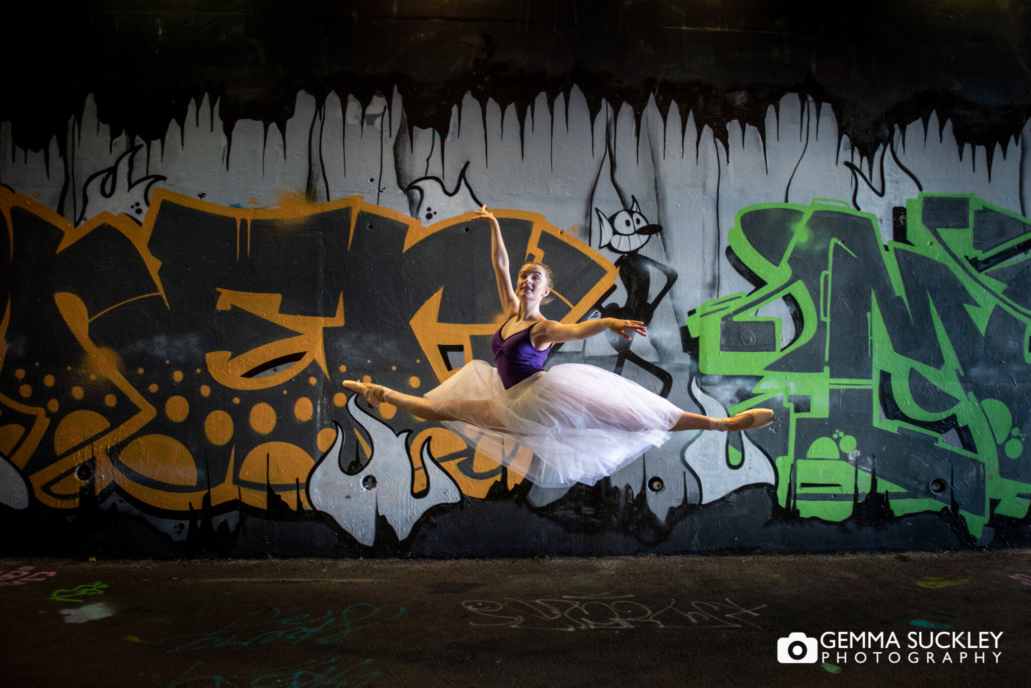 a ballet dancer leaping with a graffiti artwork being her 