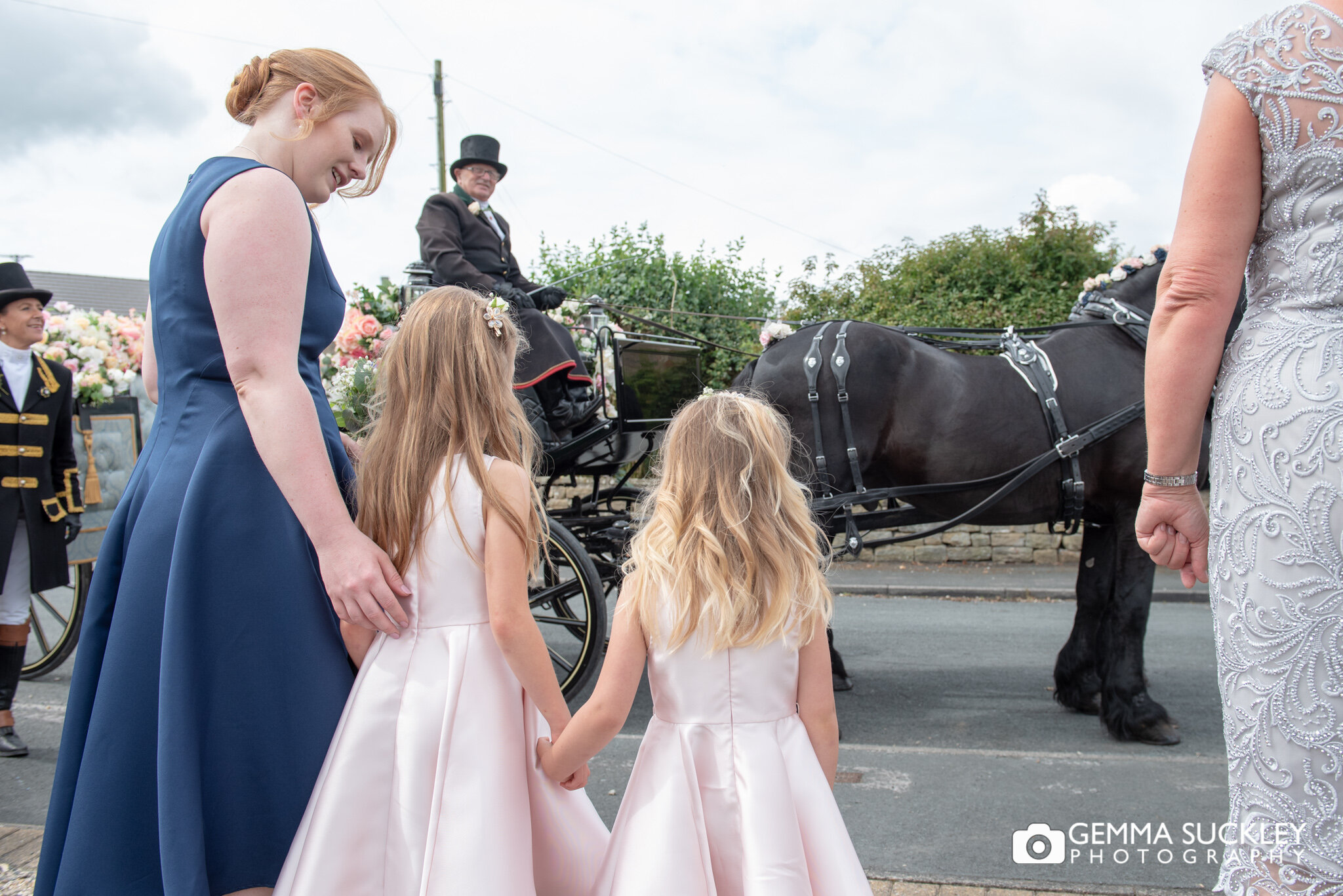 flower girls looking at the horse and carriage