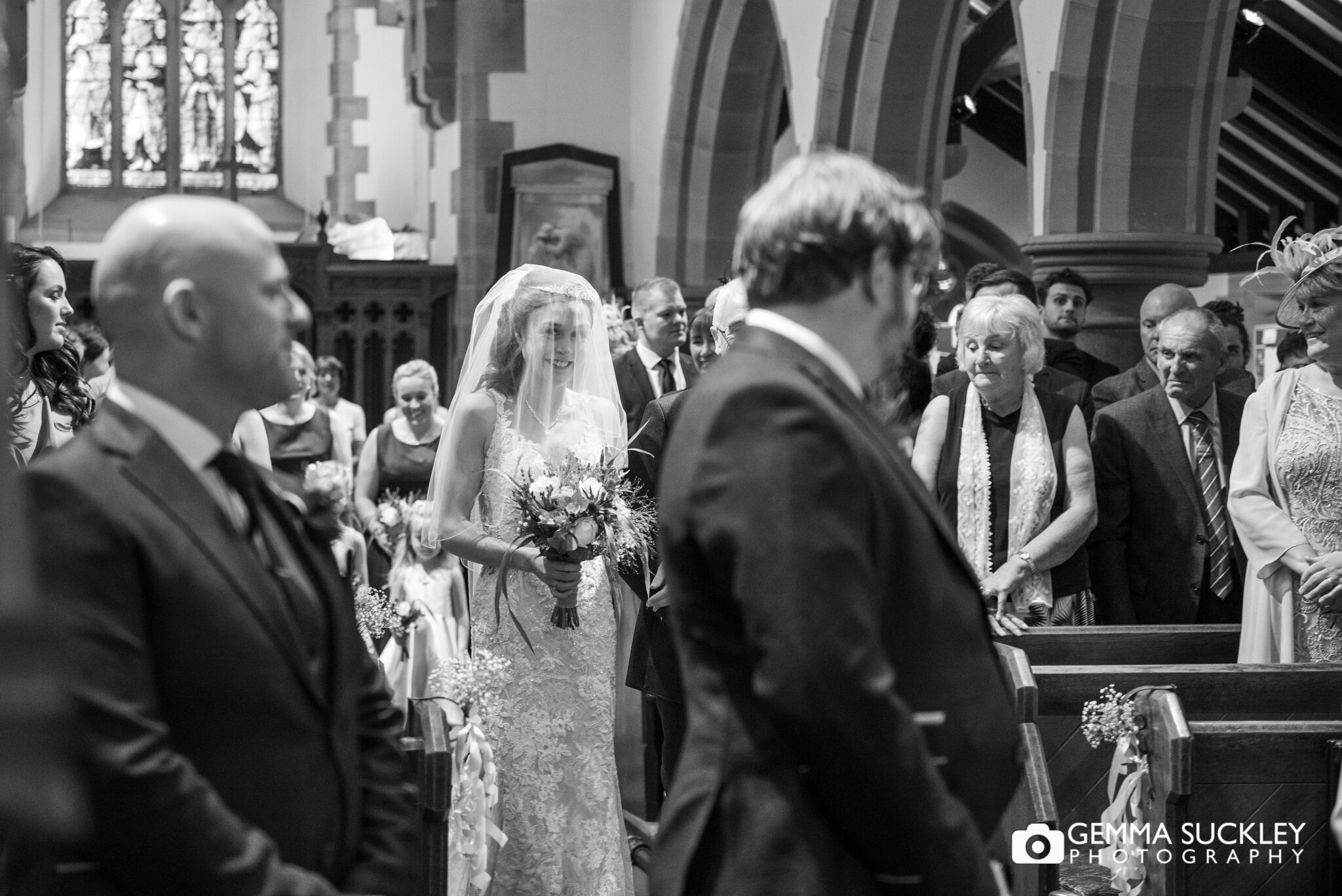 the groom turning to see his bride approach down the church aisle 