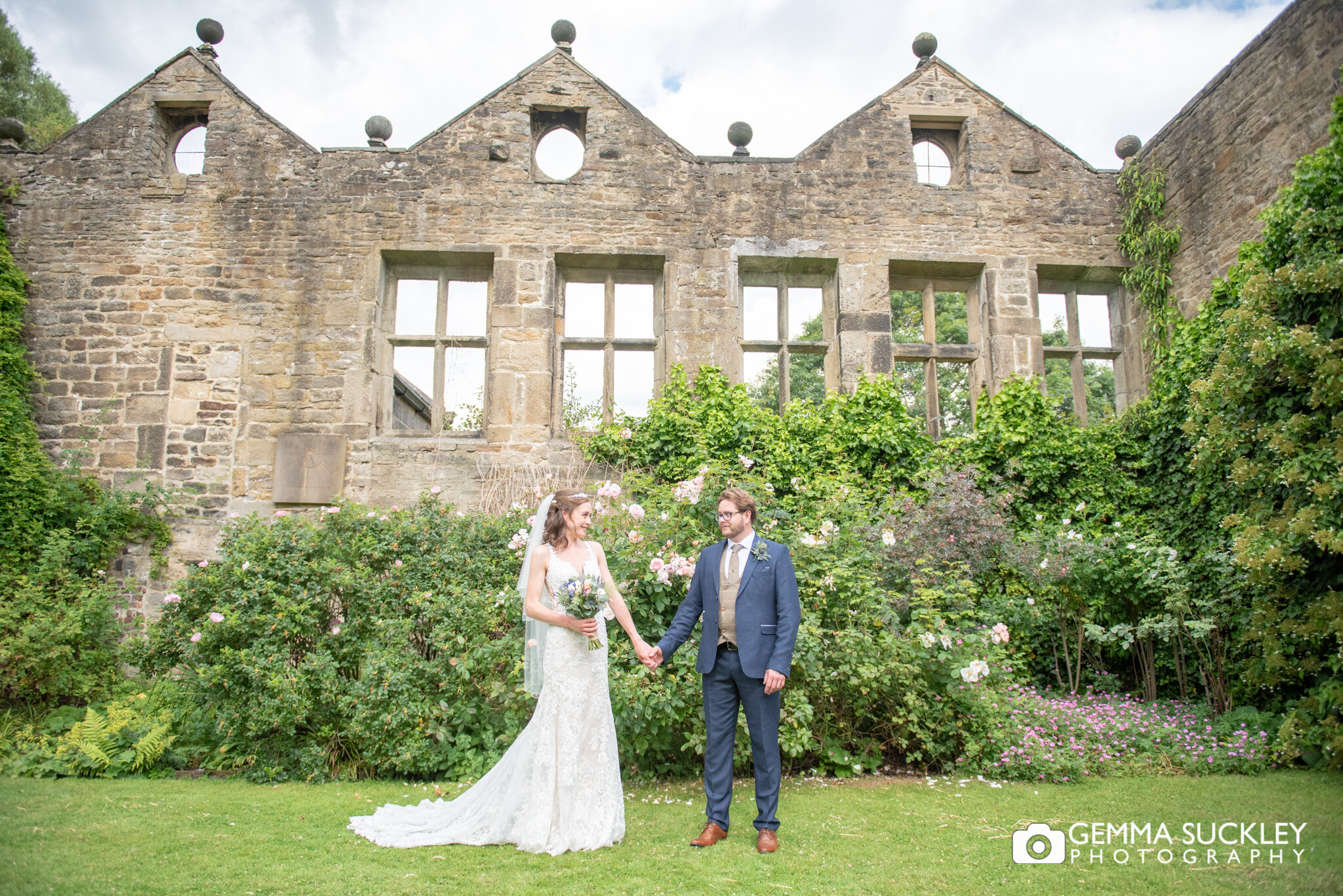 bride and groom holding hands in front of east riddlesden hall ruin