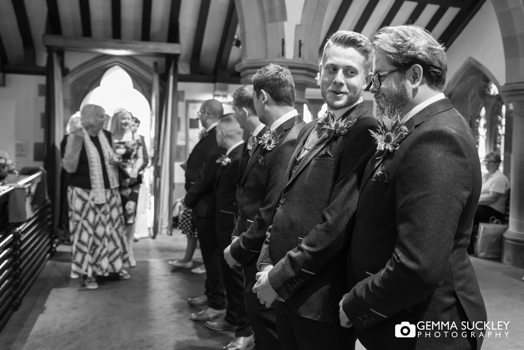 the grooms men lined up ready to meet guests at carleton church