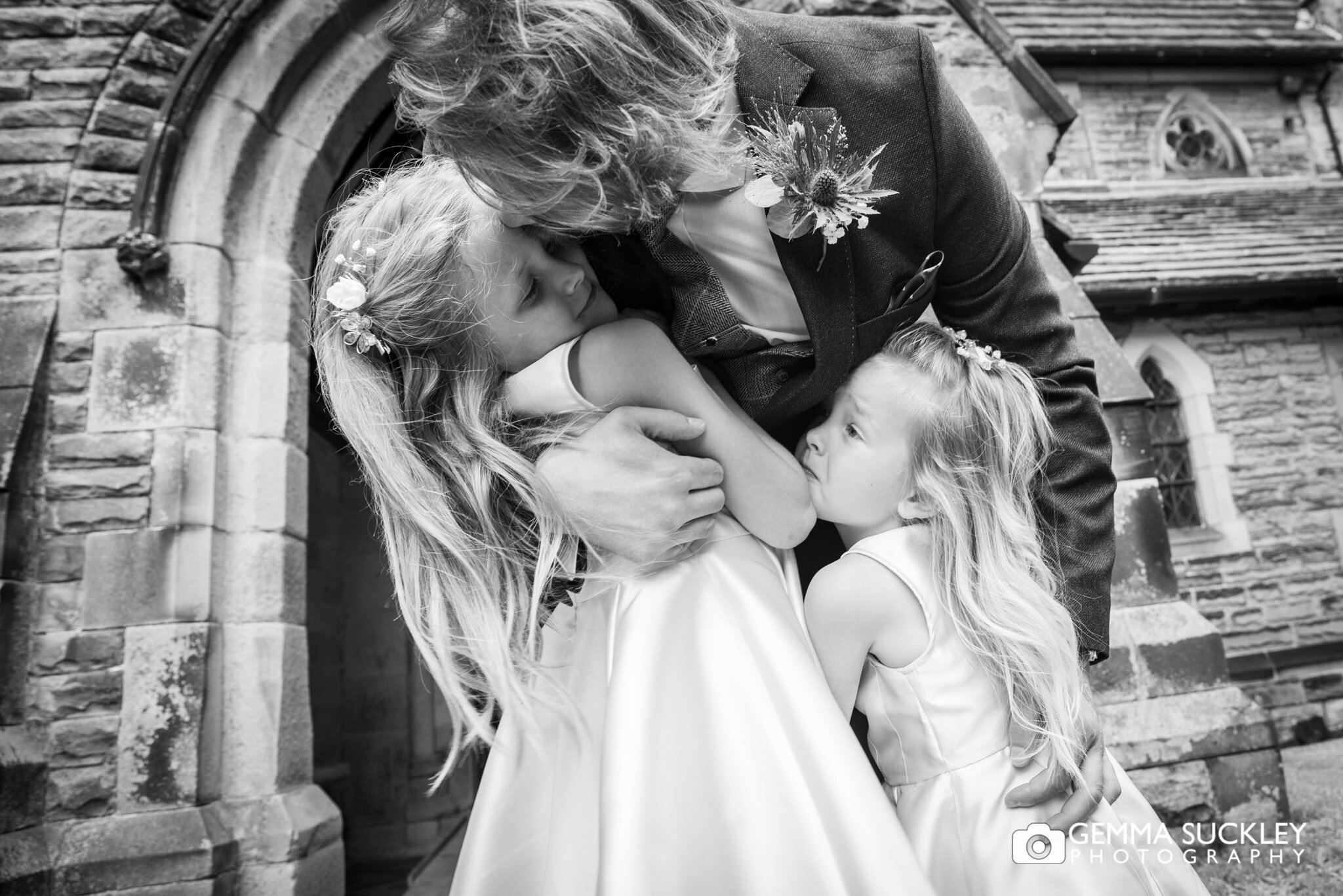 close up photo of the groom hugging his two daughters outside the church