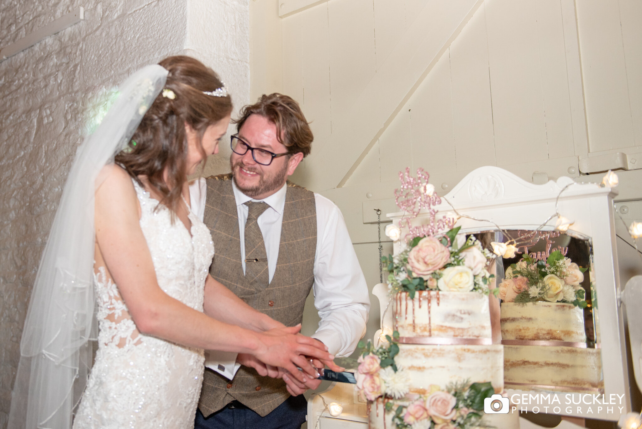 the bride and groom cut their wedding cake at east riddlsden hall wedding