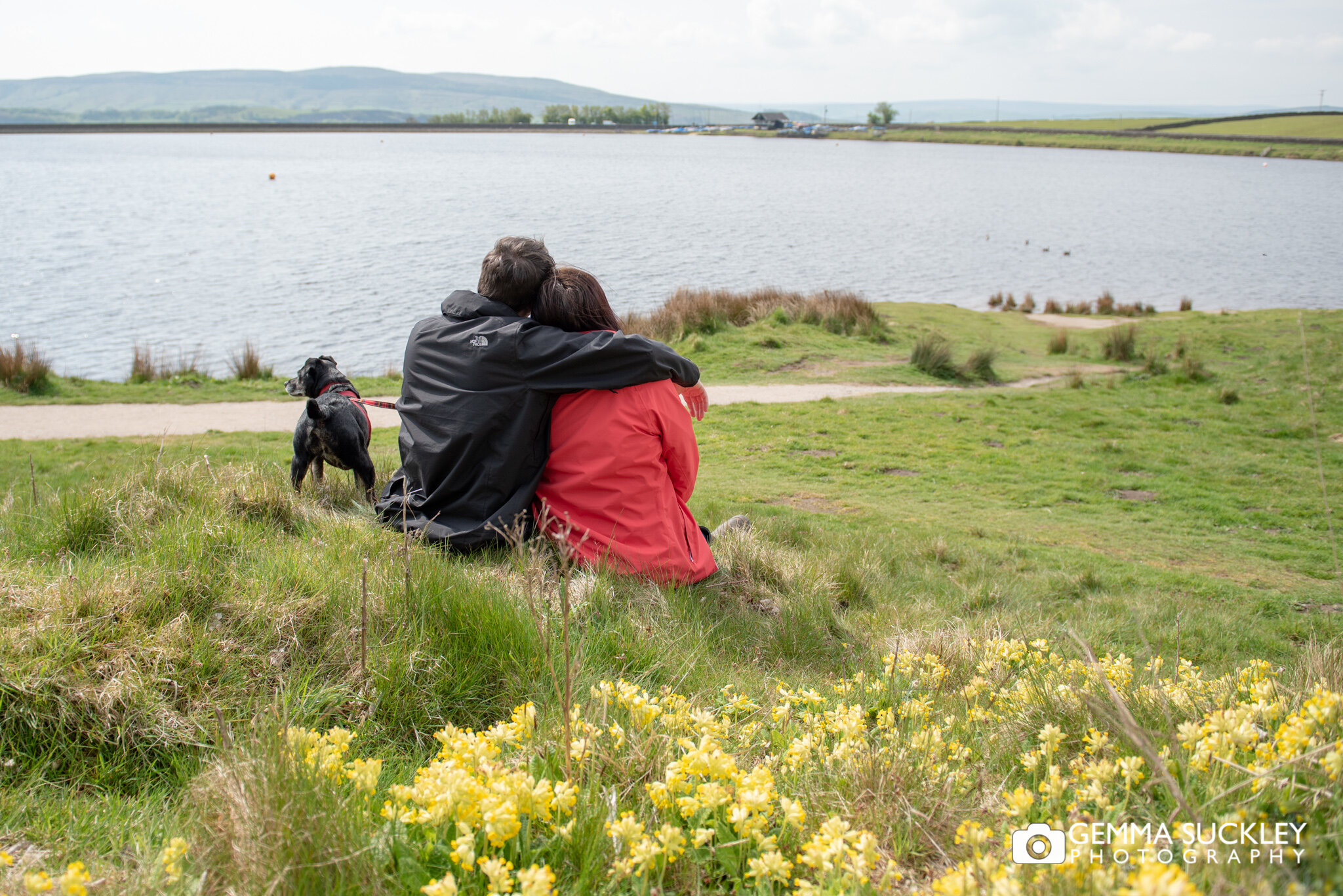 a couple and their dog sitting at embsay reservoir