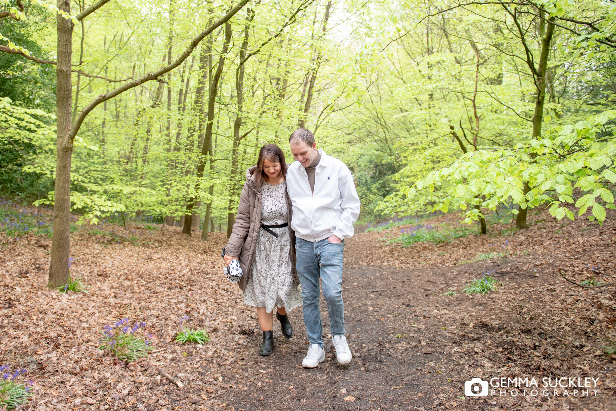 a woodland engagement photo of a couple walking in hirst wood