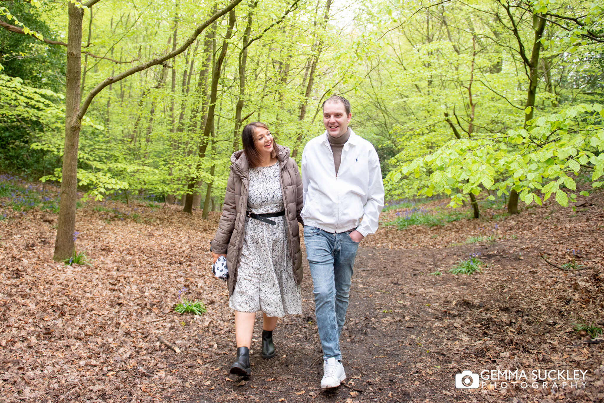 a natural engagement photo of a couple walking in hirst wood shipley