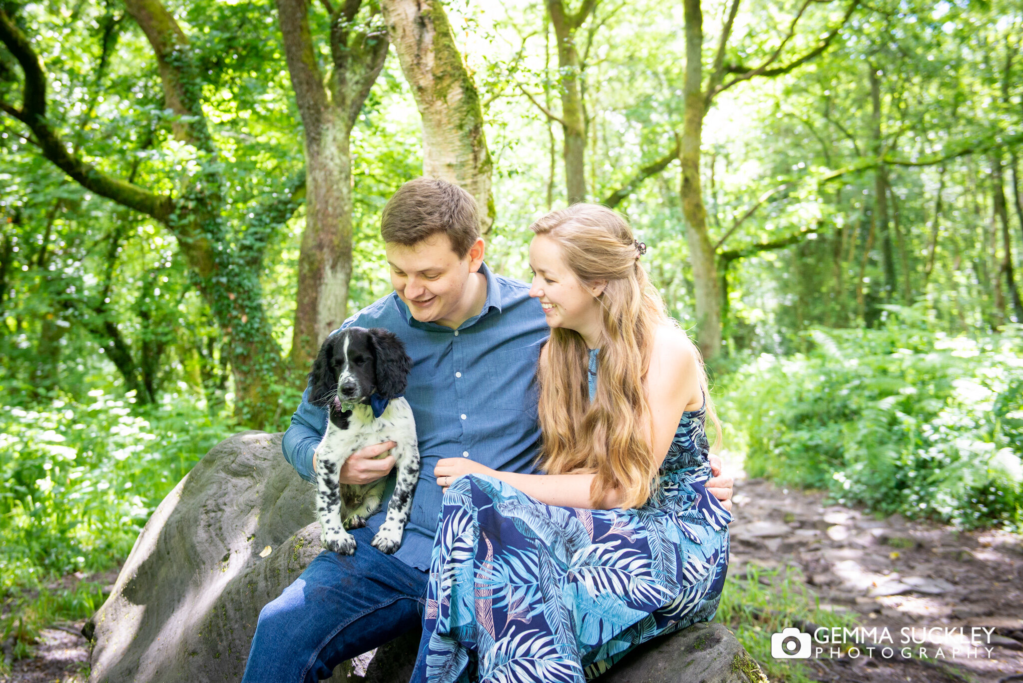 engaged couple sitting in the woods with their new puppy 