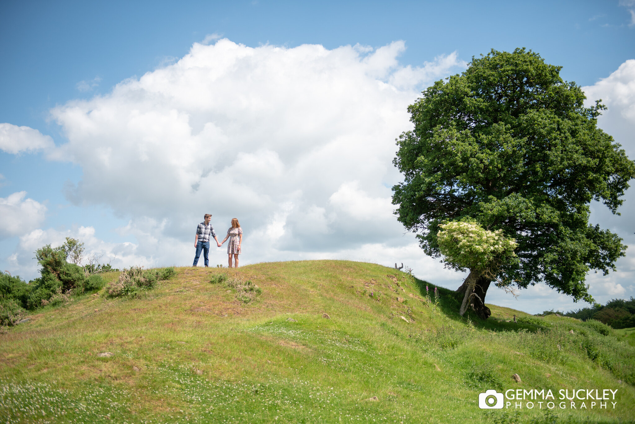 an engaged couple in the distance on a hill on harewood estae