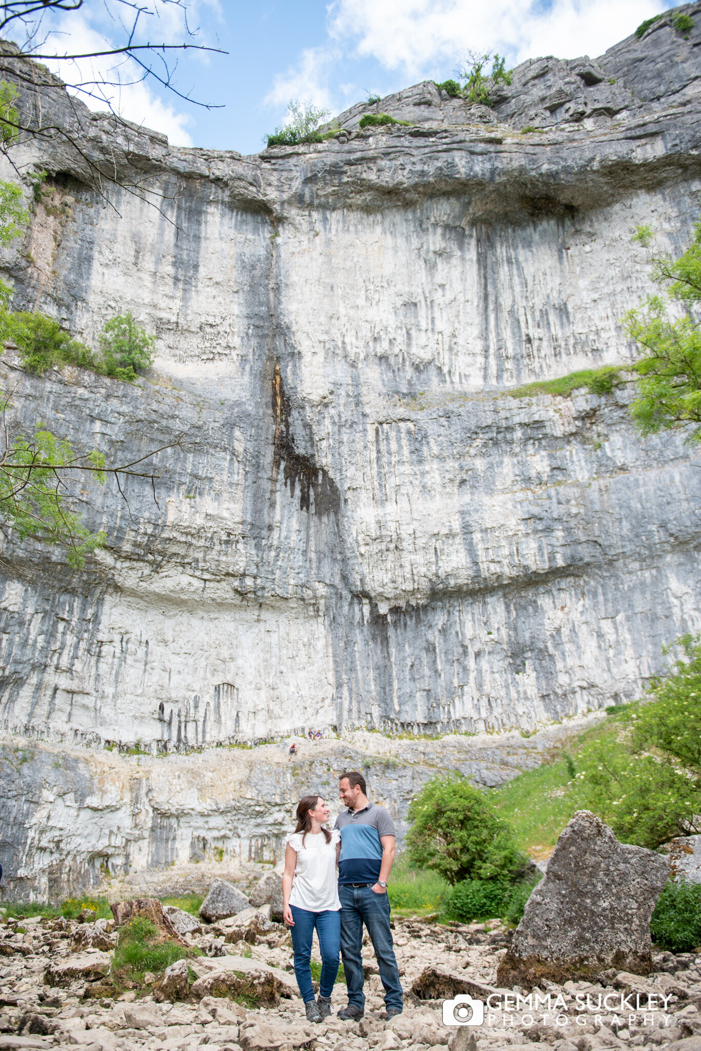 a bride and groom to be smiling for the camera at malham cove