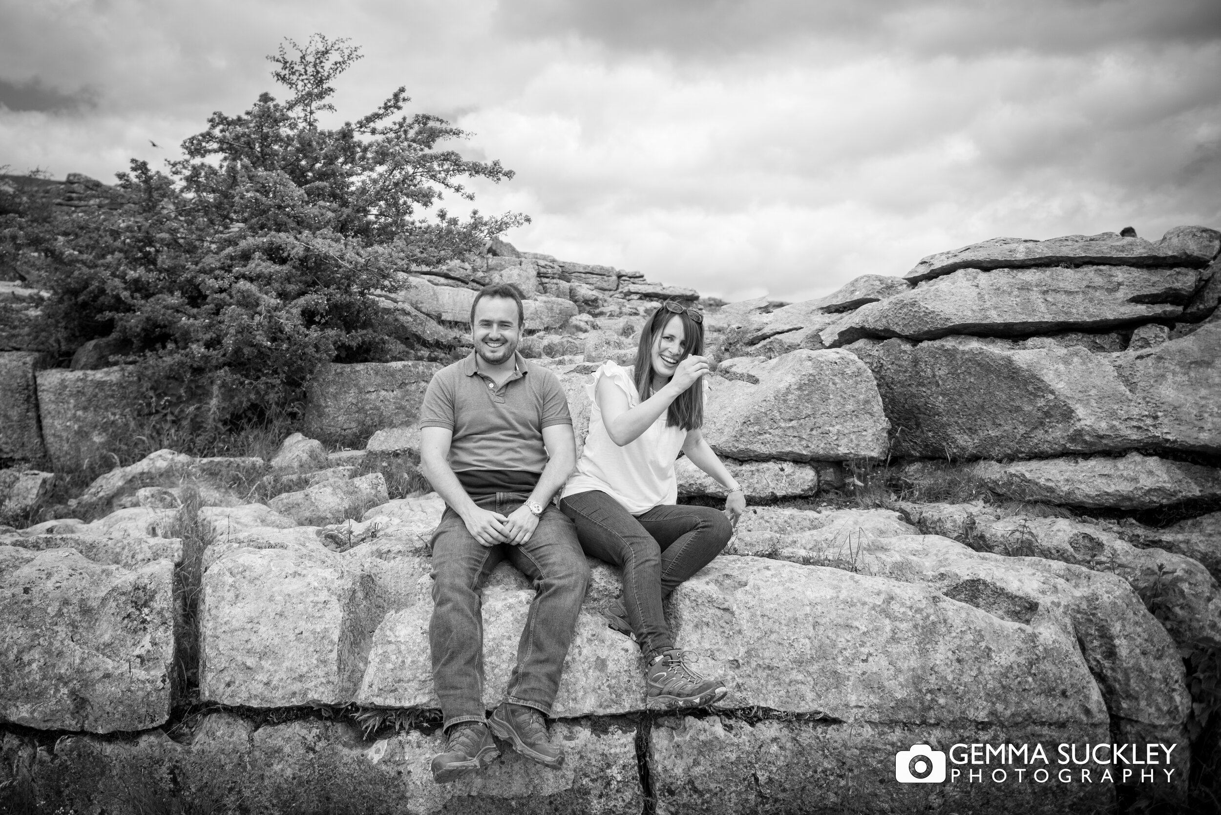 engaged couple sitting at the top of malham cove