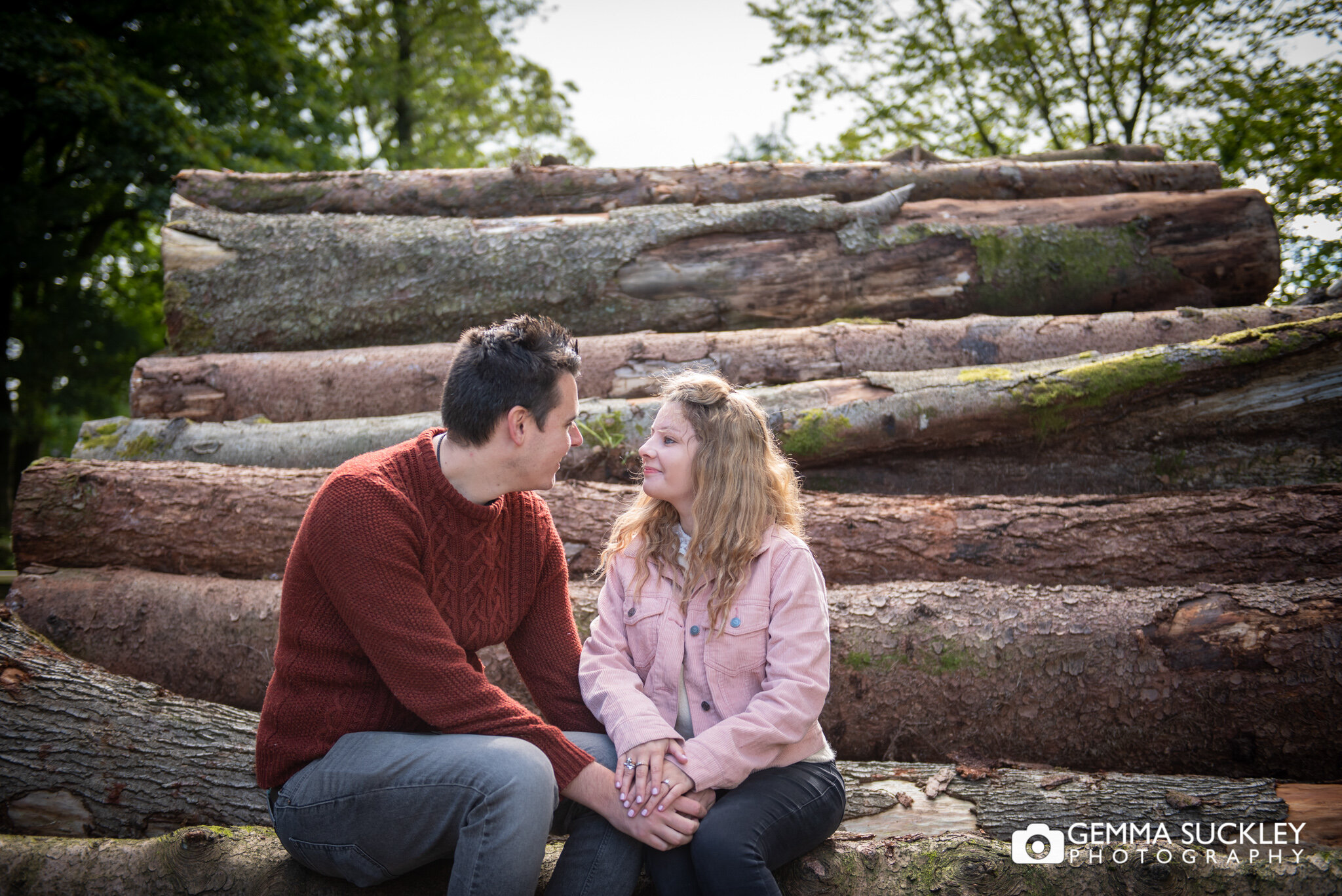 a couple sitting on the logs at browsholme hall in clitheroe