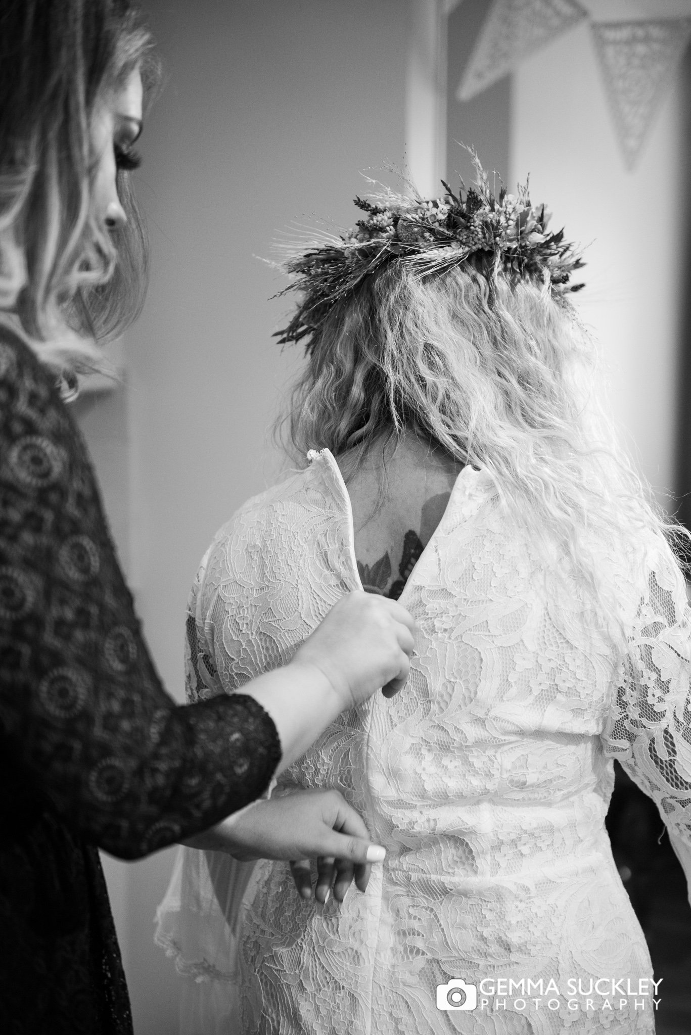 a bridesmaid zipping up the brides dress